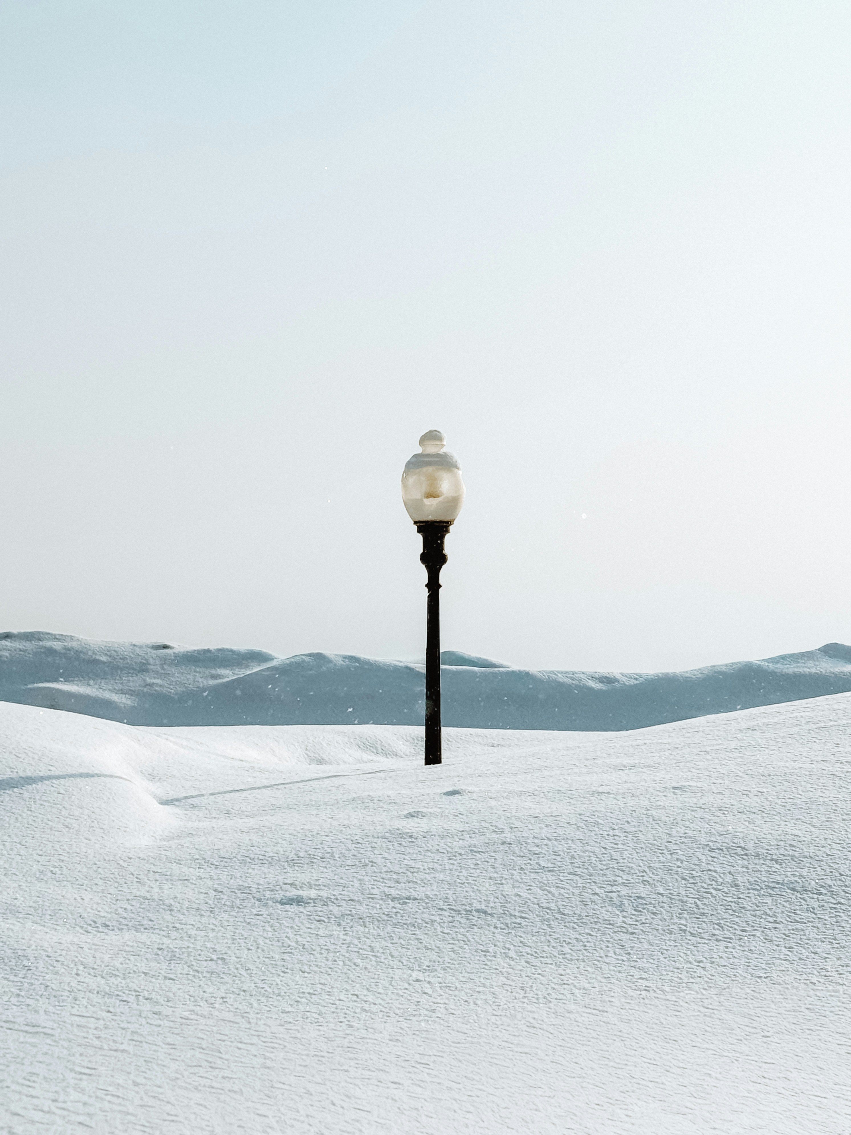 A solitary lamppost stands in a snow-covered landscape