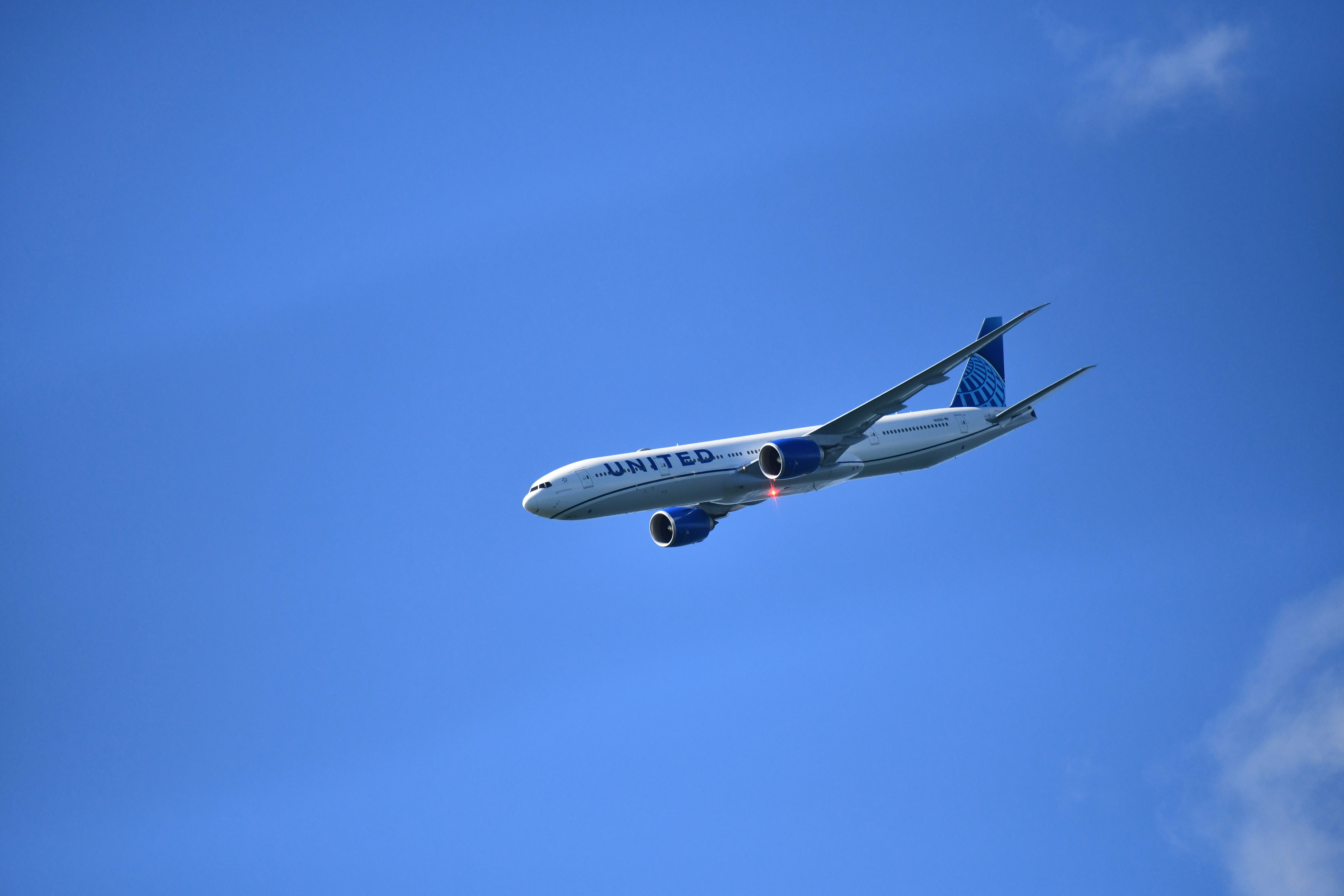 A united airlines airplane flies in the clear blue sky.