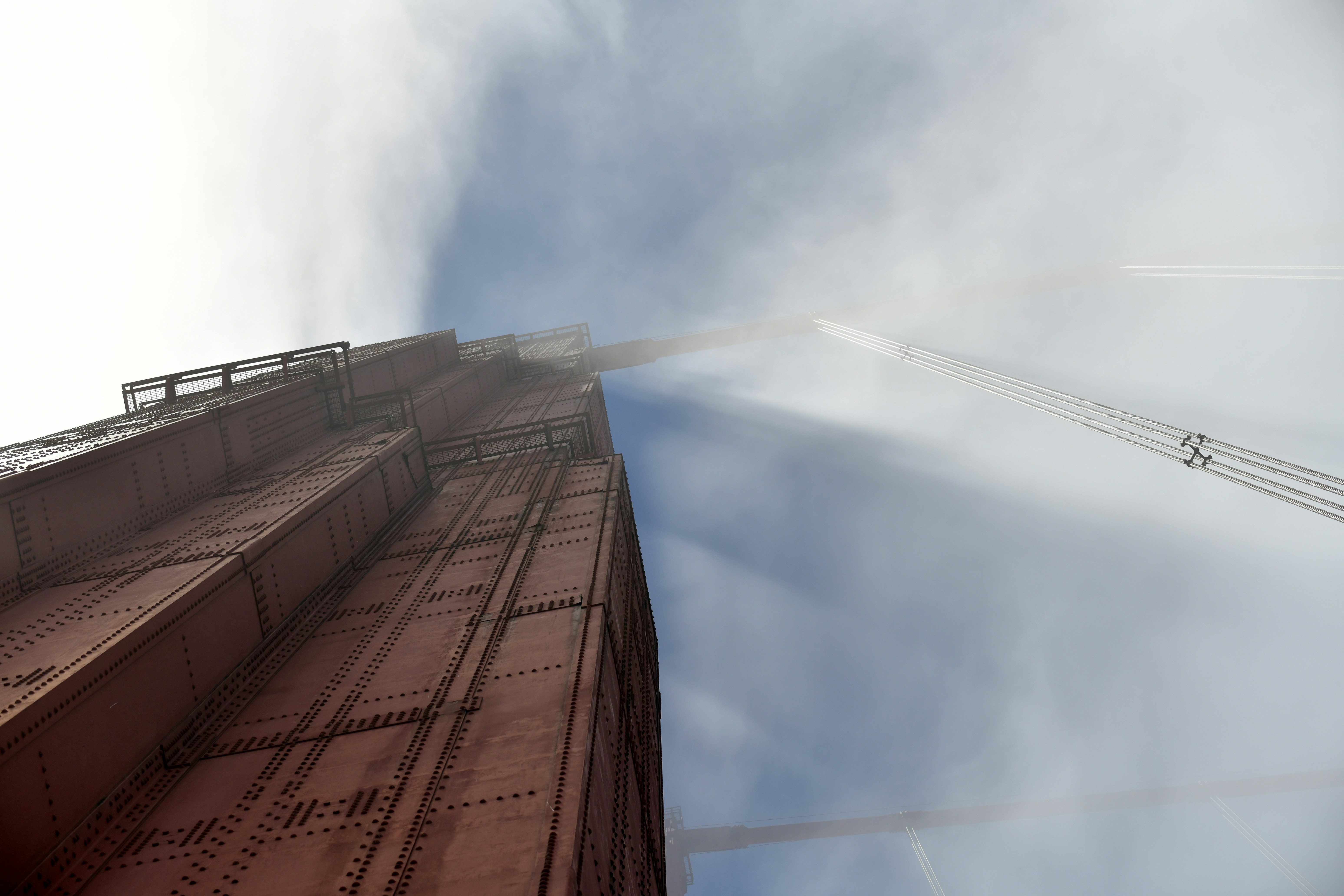 Looking upwards at a metal clad tower that disappears into mist.
