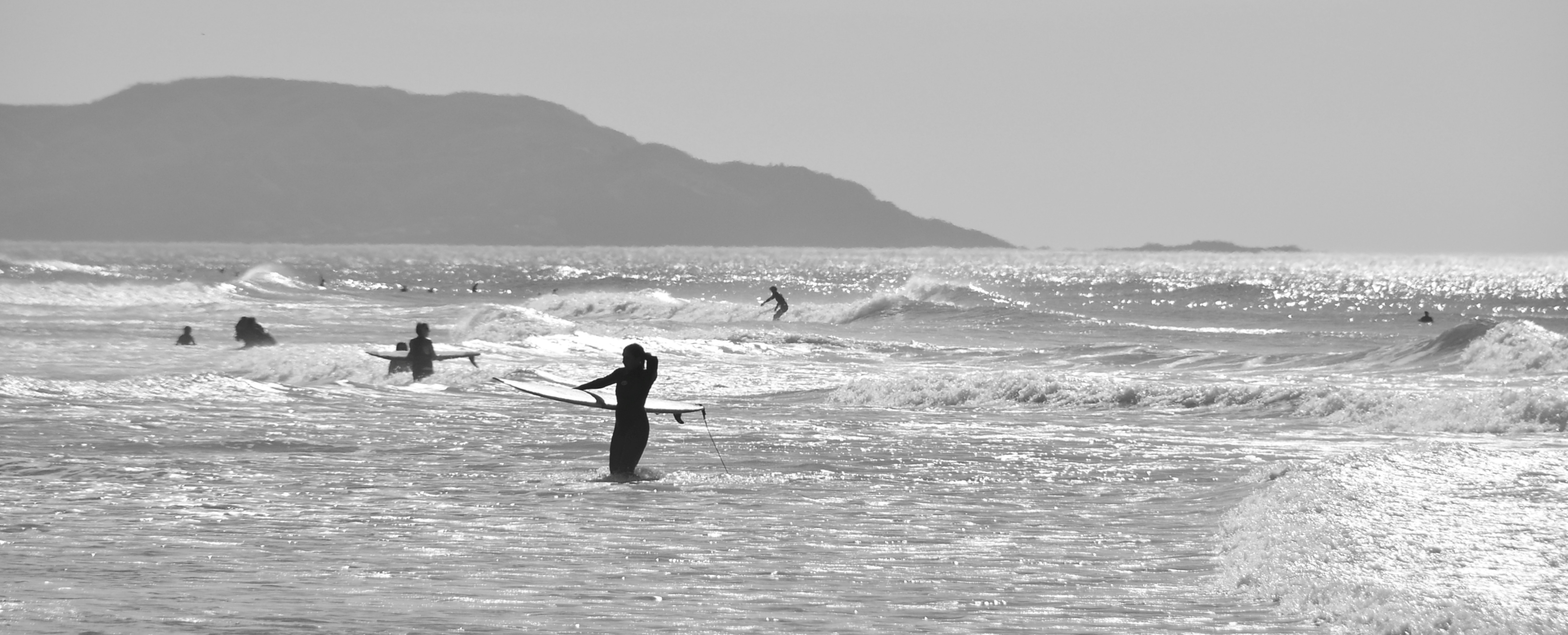 Surfers in the ocean with a distant mountain