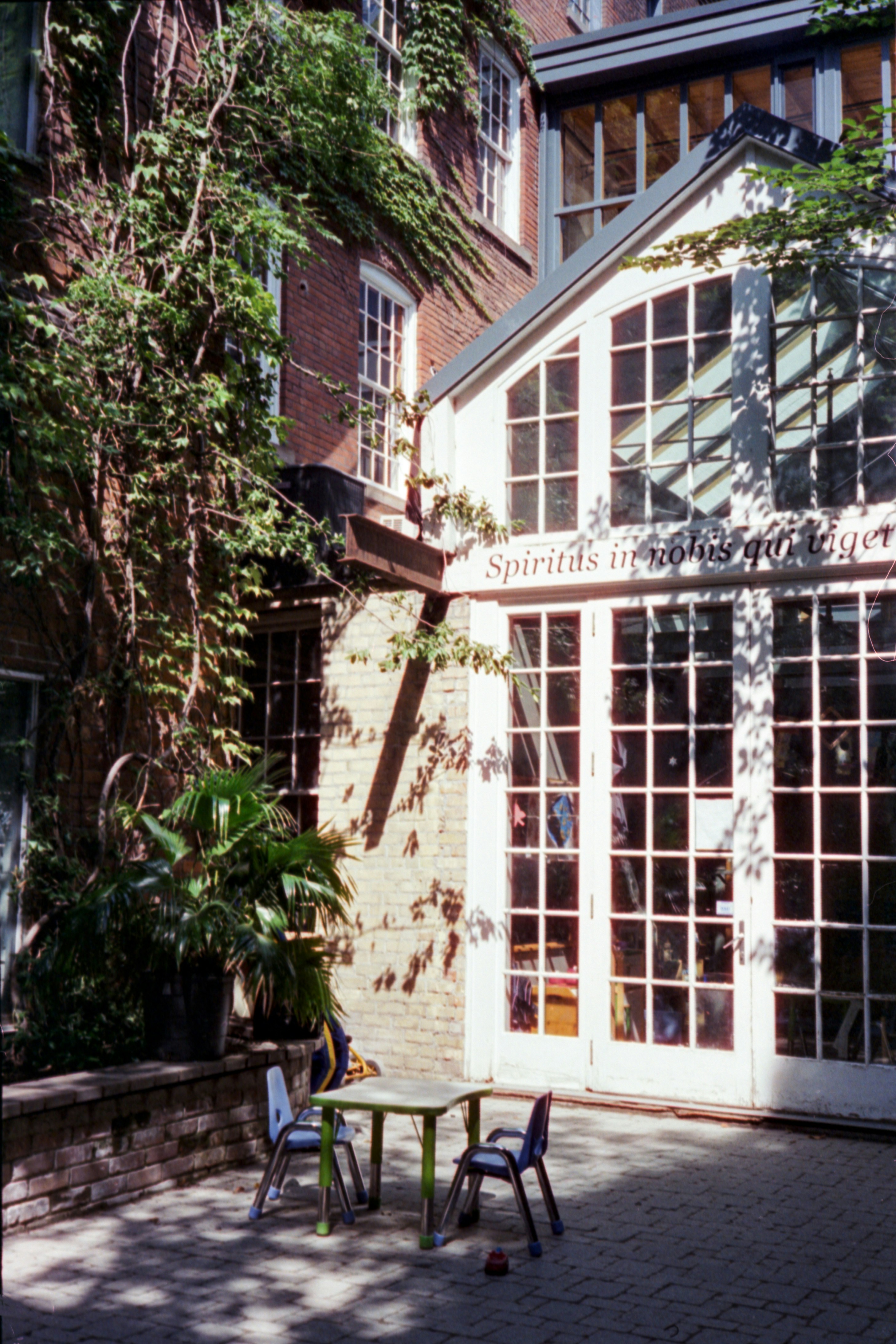 Two chairs and a table in a sunny courtyard.