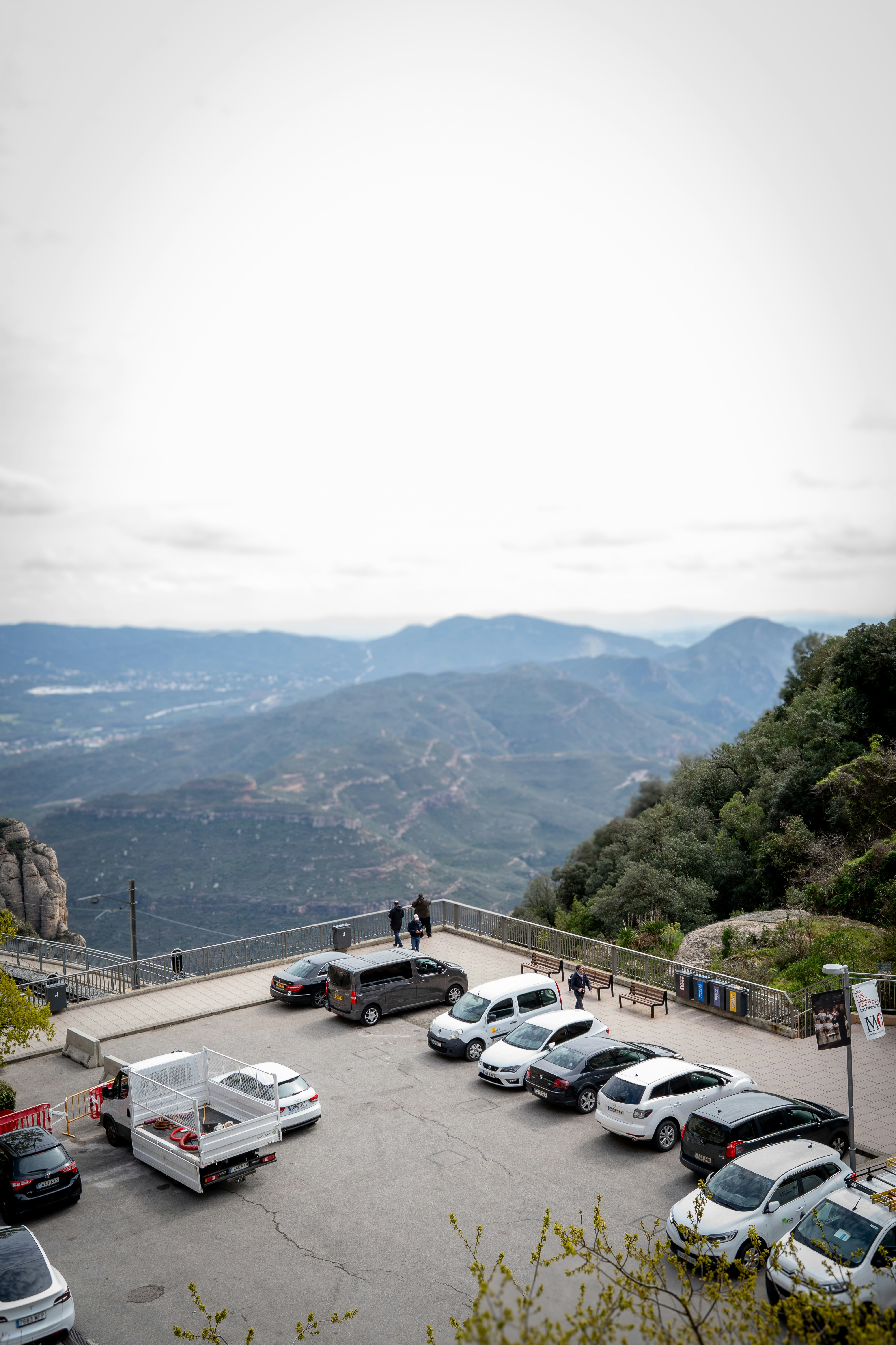 Cars parked on a scenic overlook with mountains in background.