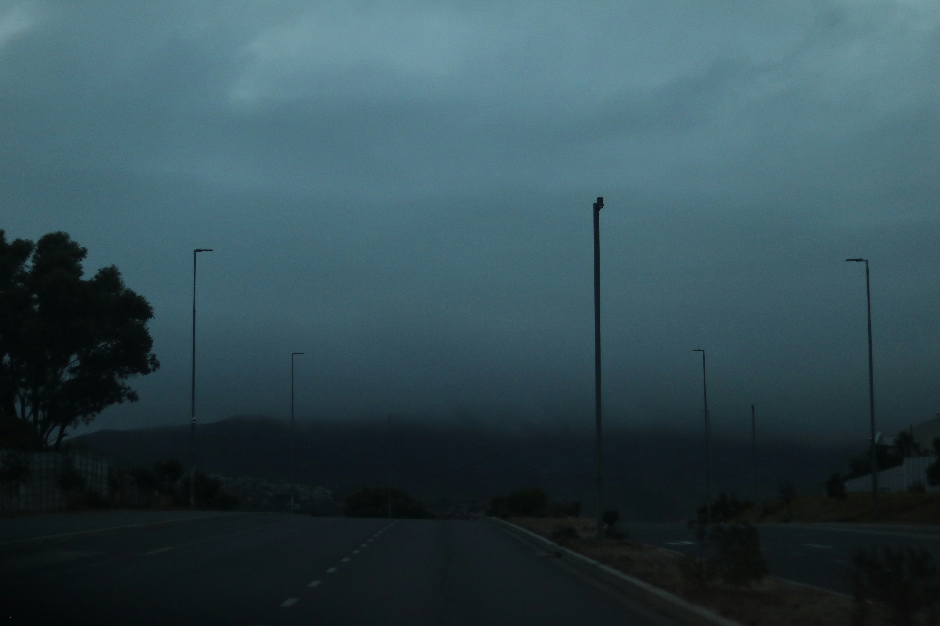 Dunkler, stürmischer Himmel über einer trostlosen Straße mit Straßenlaternen.