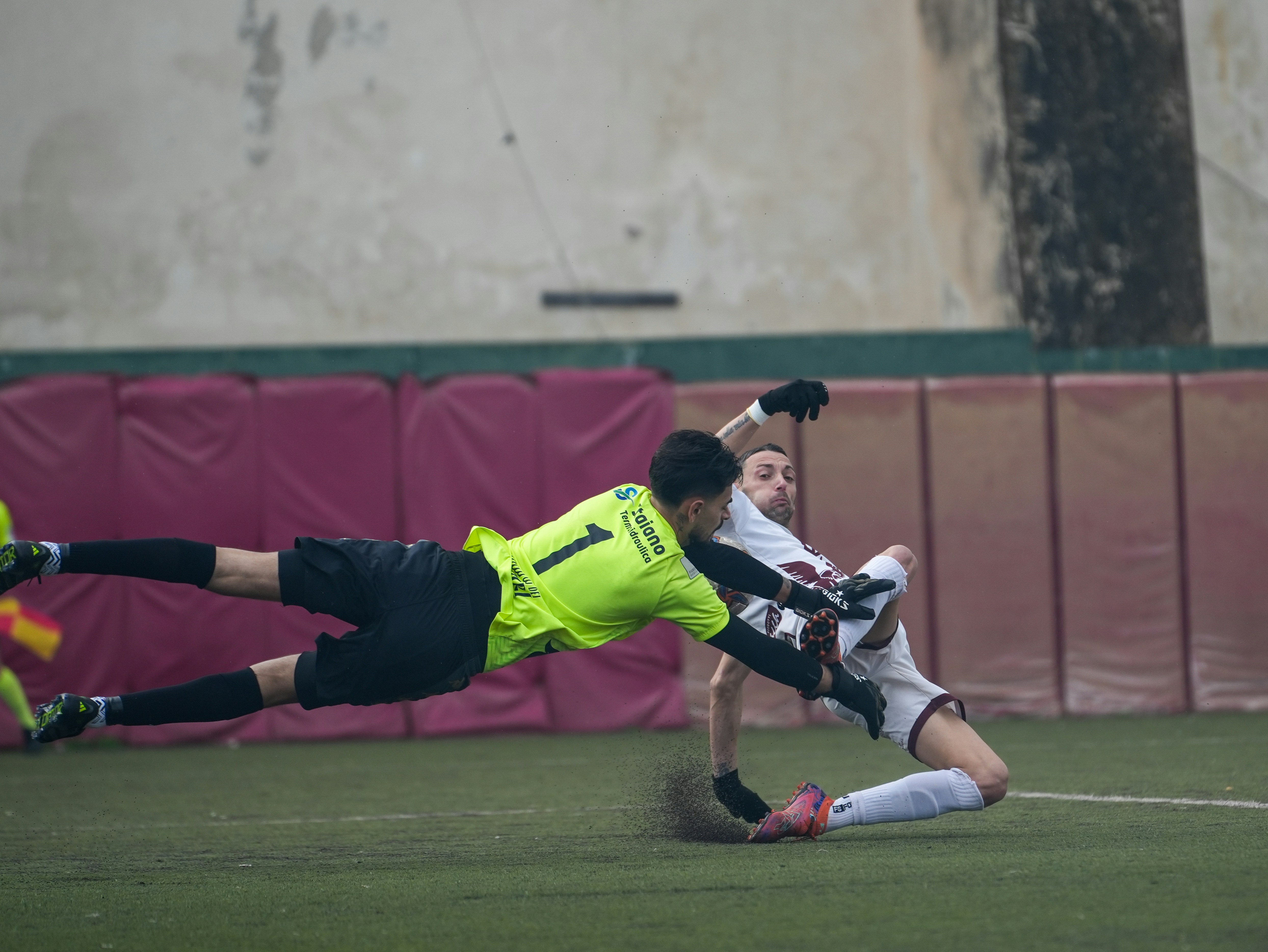 Le gardien plonge pour sauver un ballon de football pendant un match.