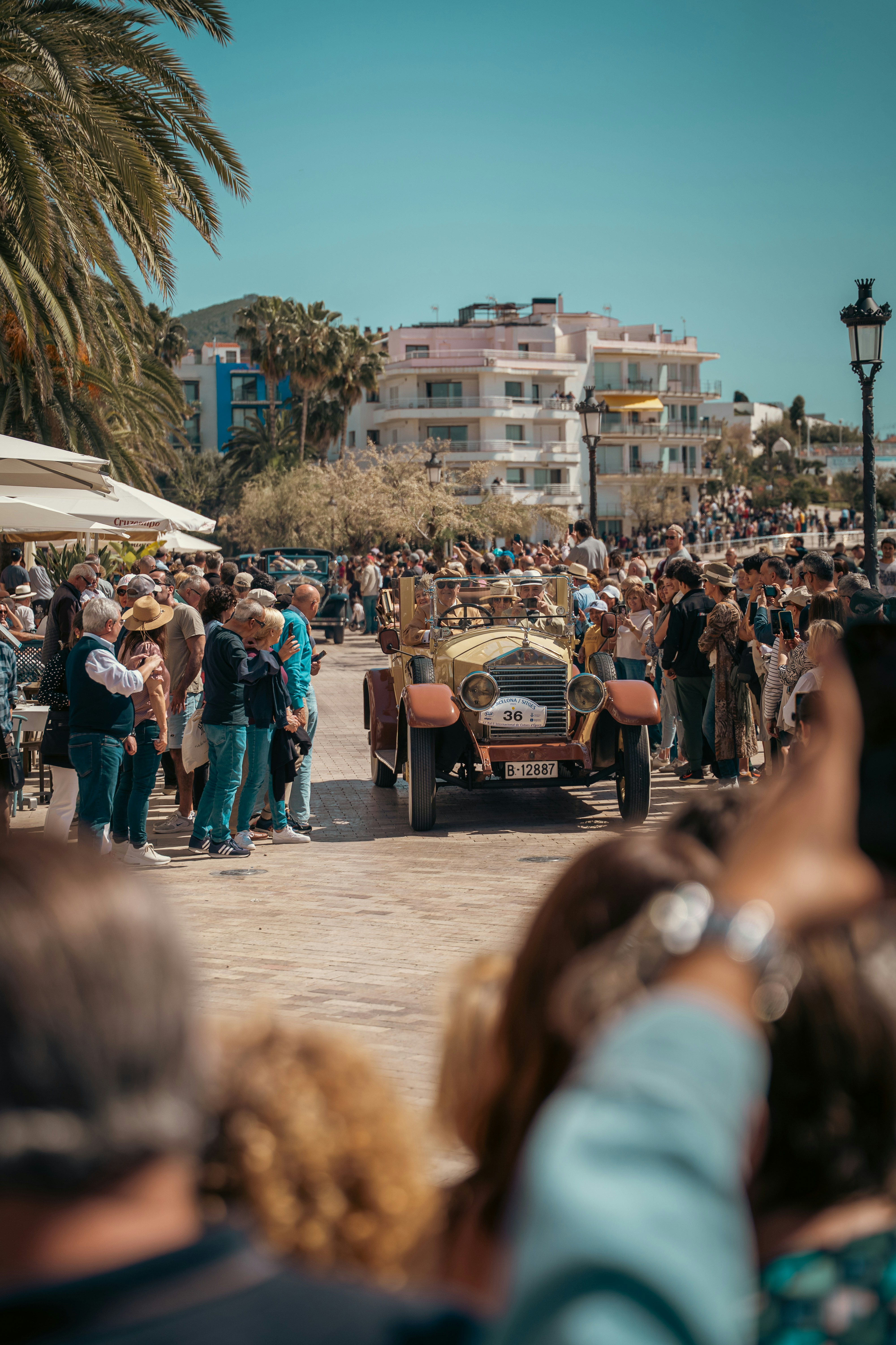 Vintage car drives through a crowd of spectators