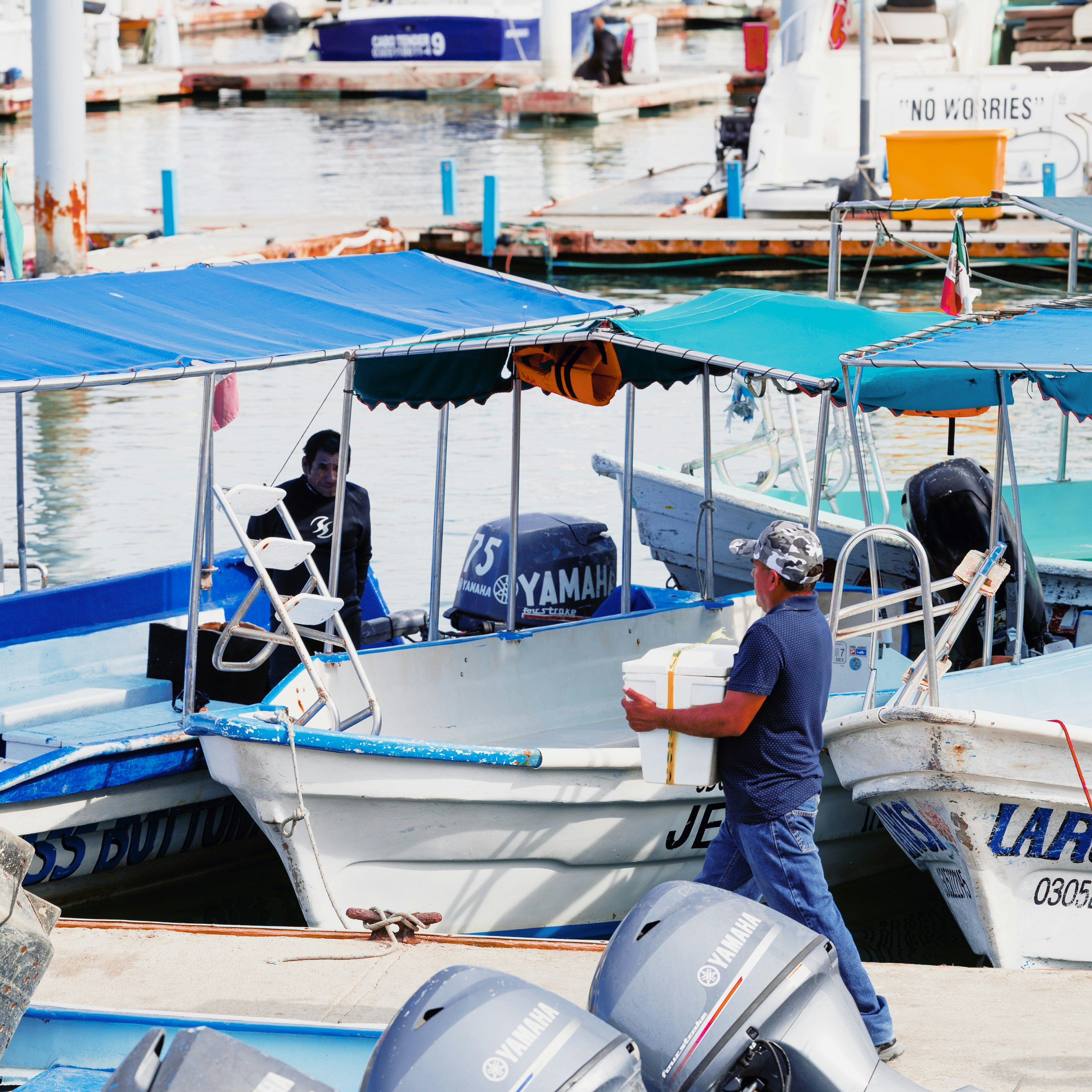Männer, die Kisten auf Boote an einem Yachthafen transportieren