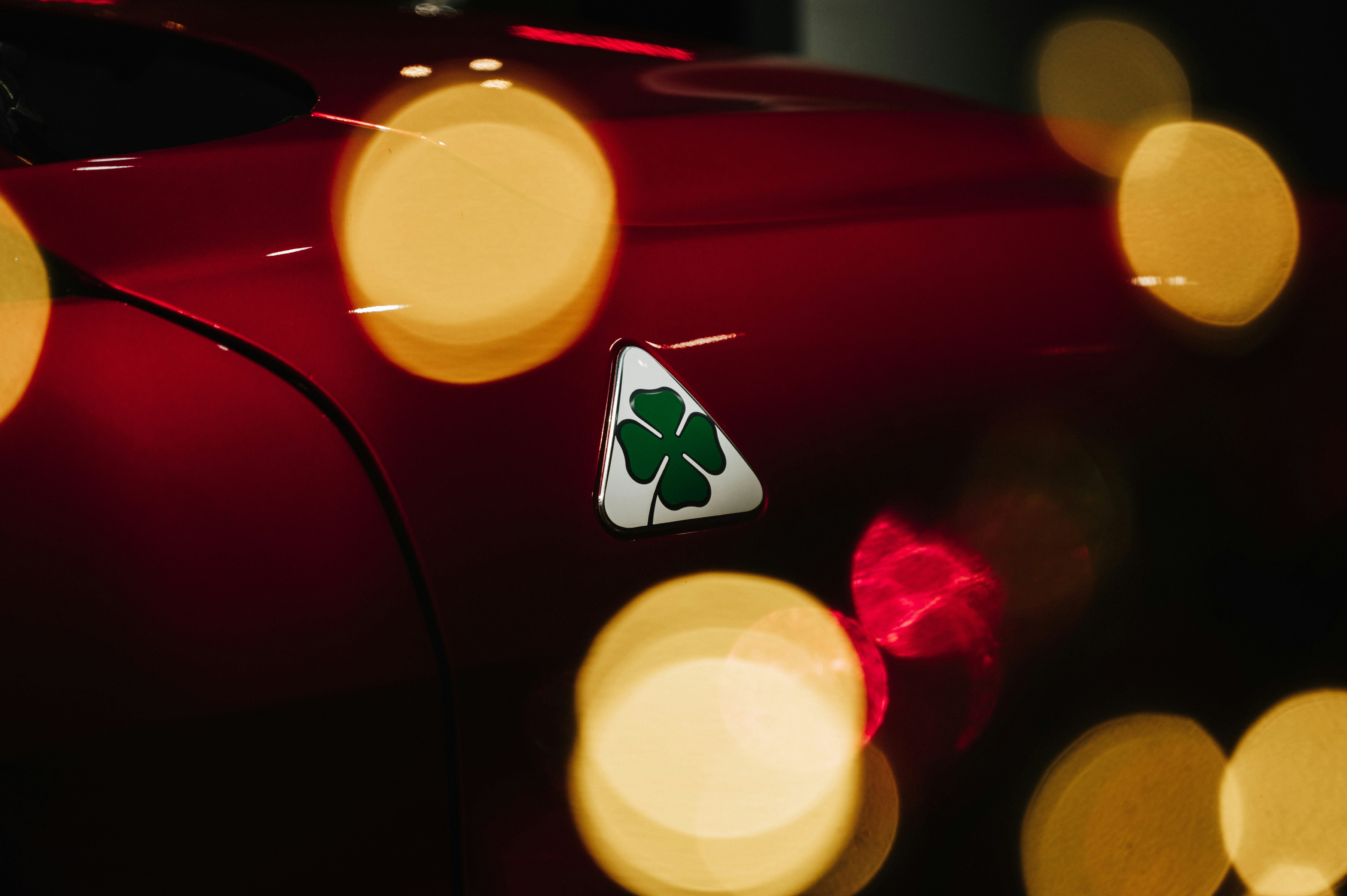 Red car with a clover emblem and bokeh lights