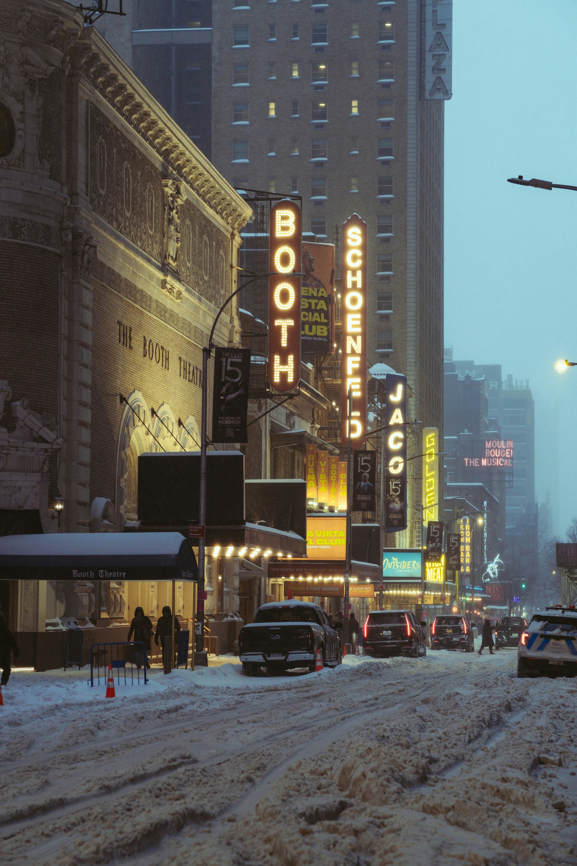 Snowy street scene with theater marquees at night