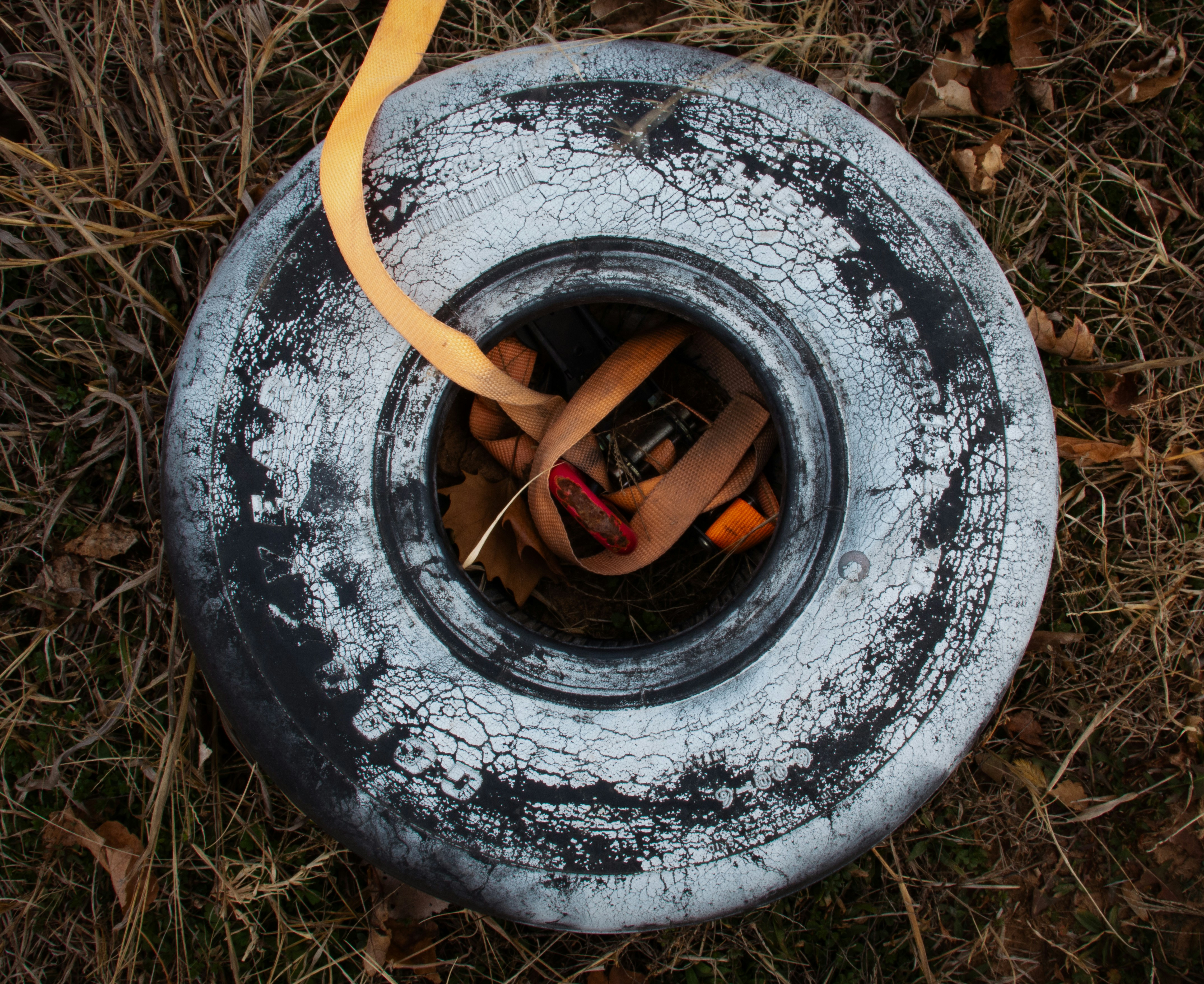 Old weathered tire lying on dry grass