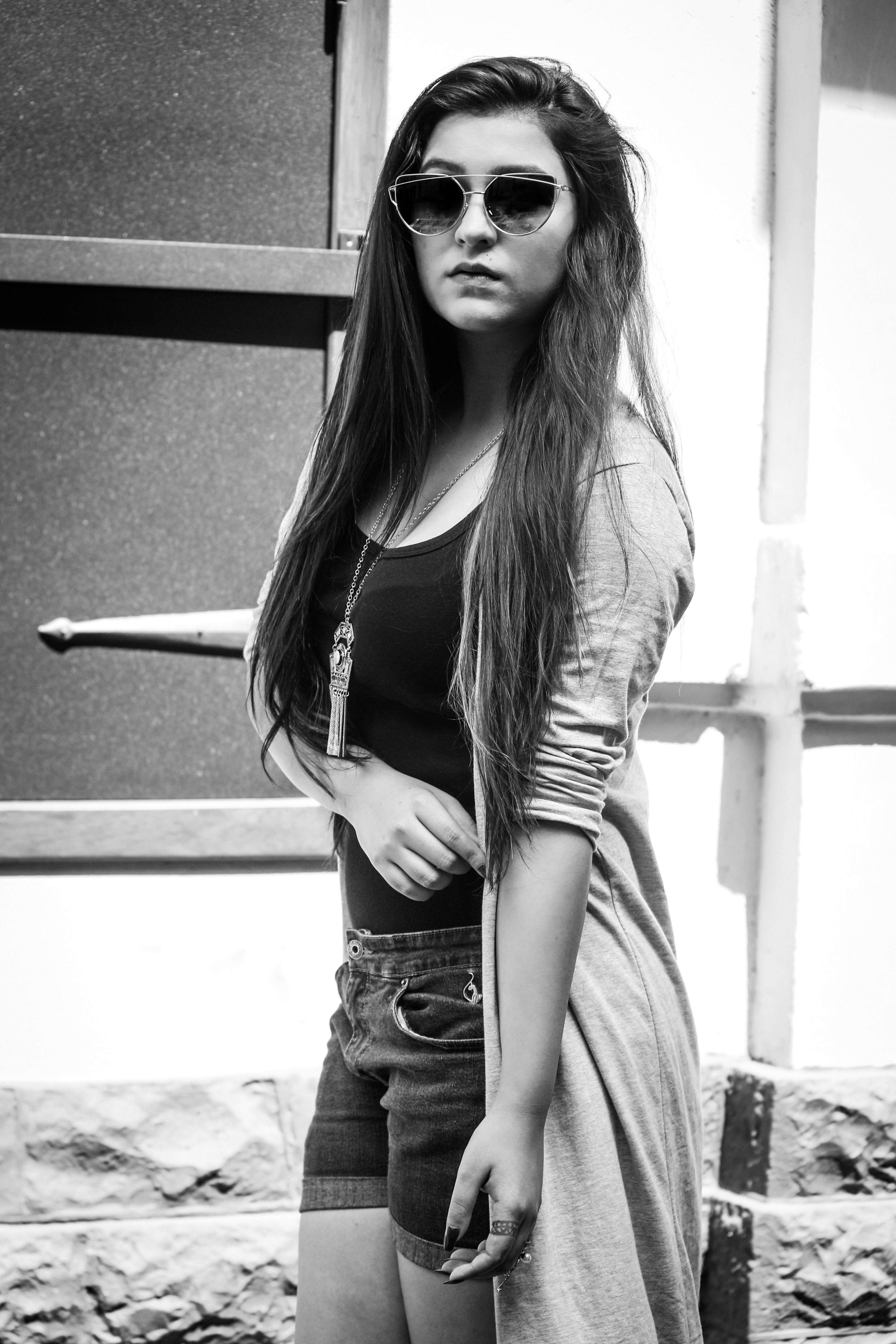 Young woman in sunglasses and cardigan outdoors