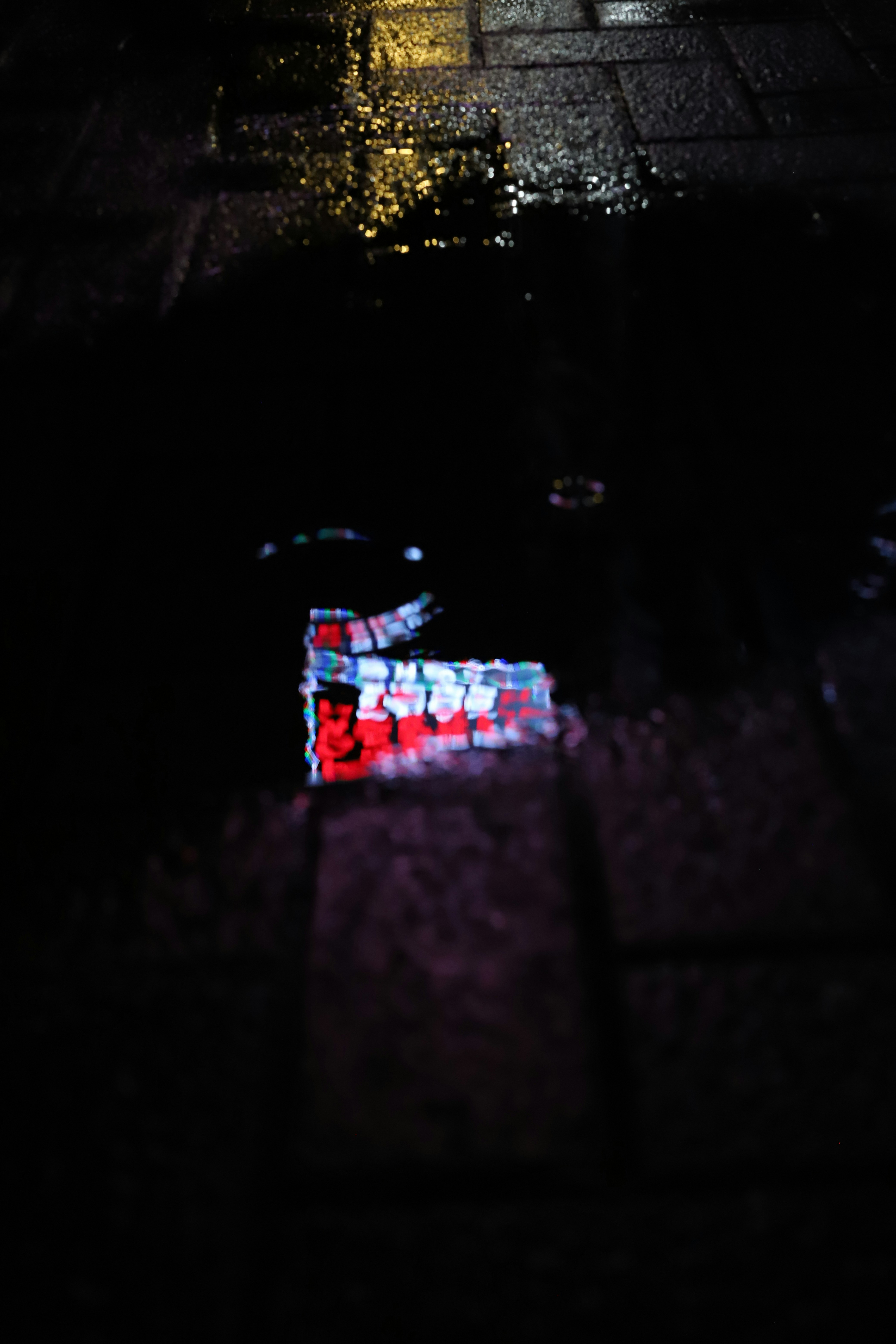 Colorful light reflects on wet pavement at night