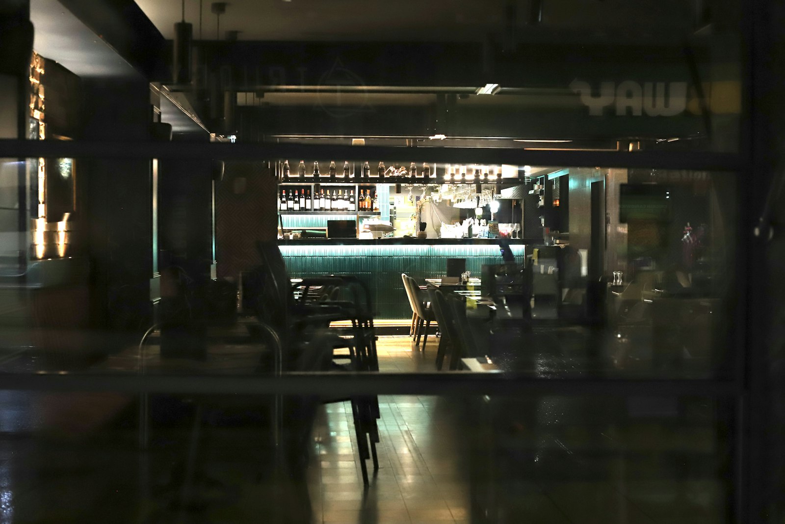 Empty, dimly lit bar interior with a glowing wood counter