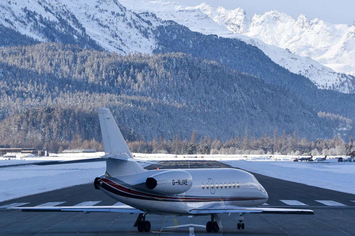 Private jet on a snowy runway with alpine mountains behind