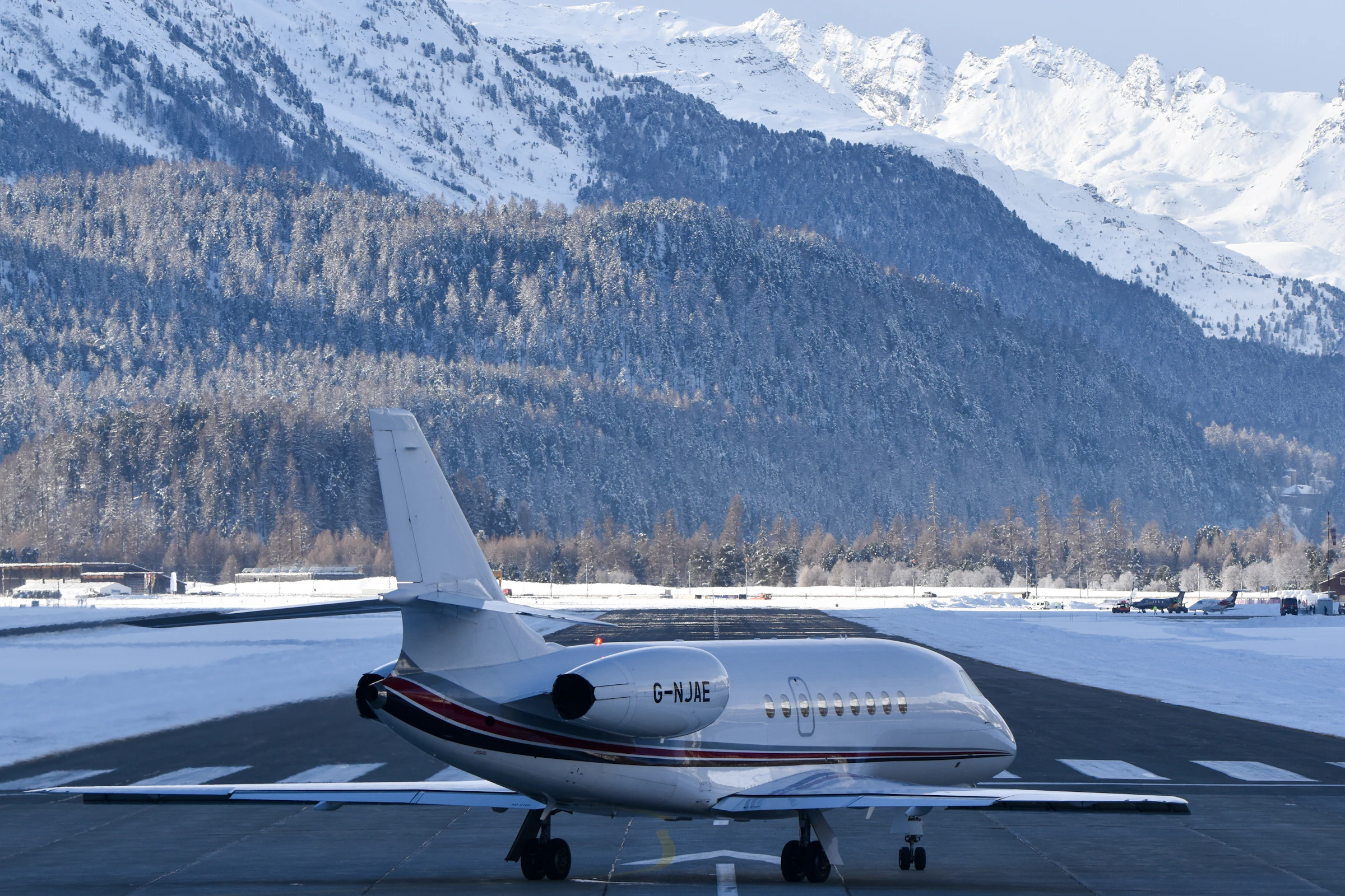 Dassault Falcon tri-jet on a snowy Alpine runway beneath the mountains