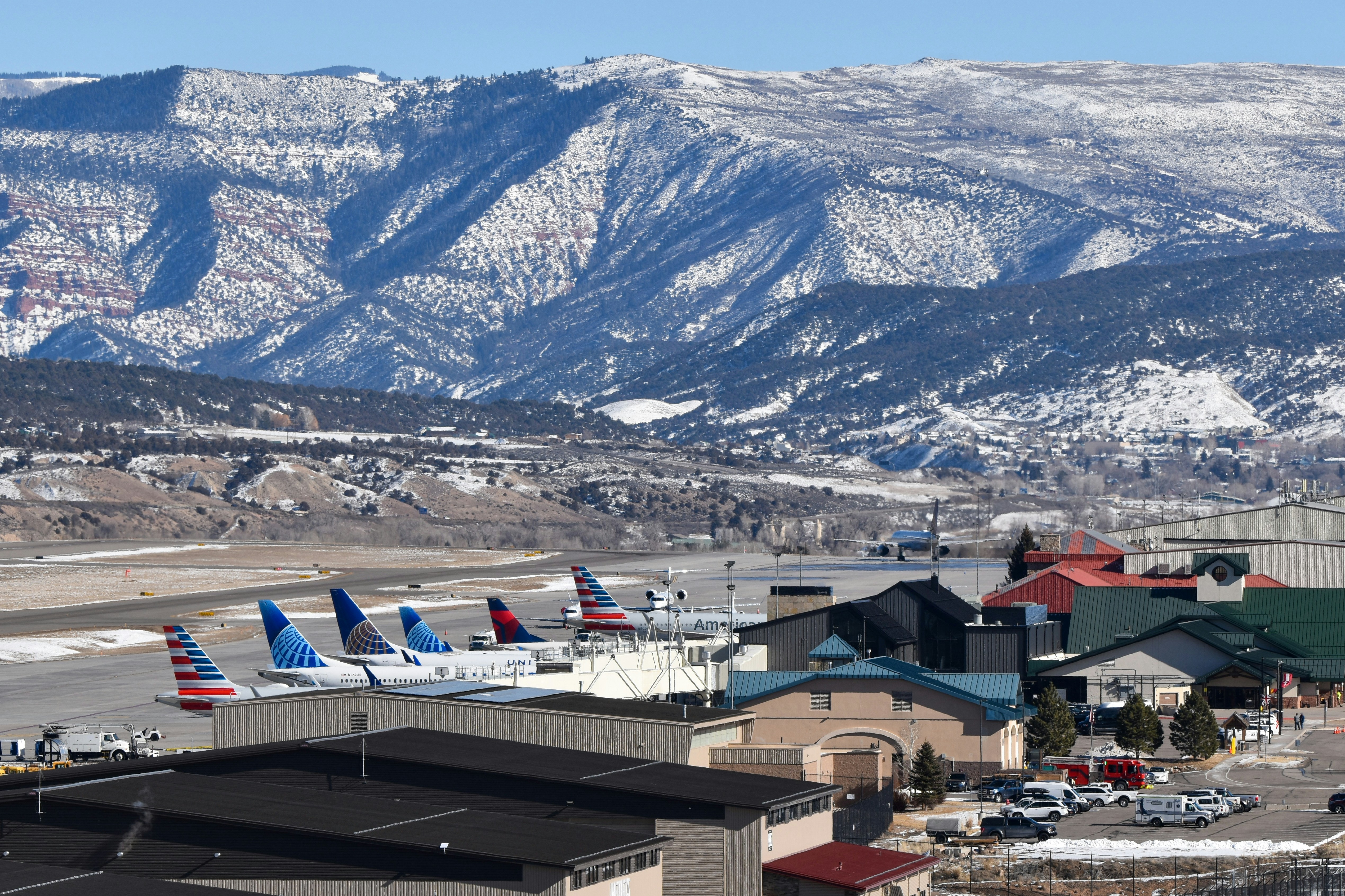Aviones en un aeropuerto con montañas nevadas detrás.