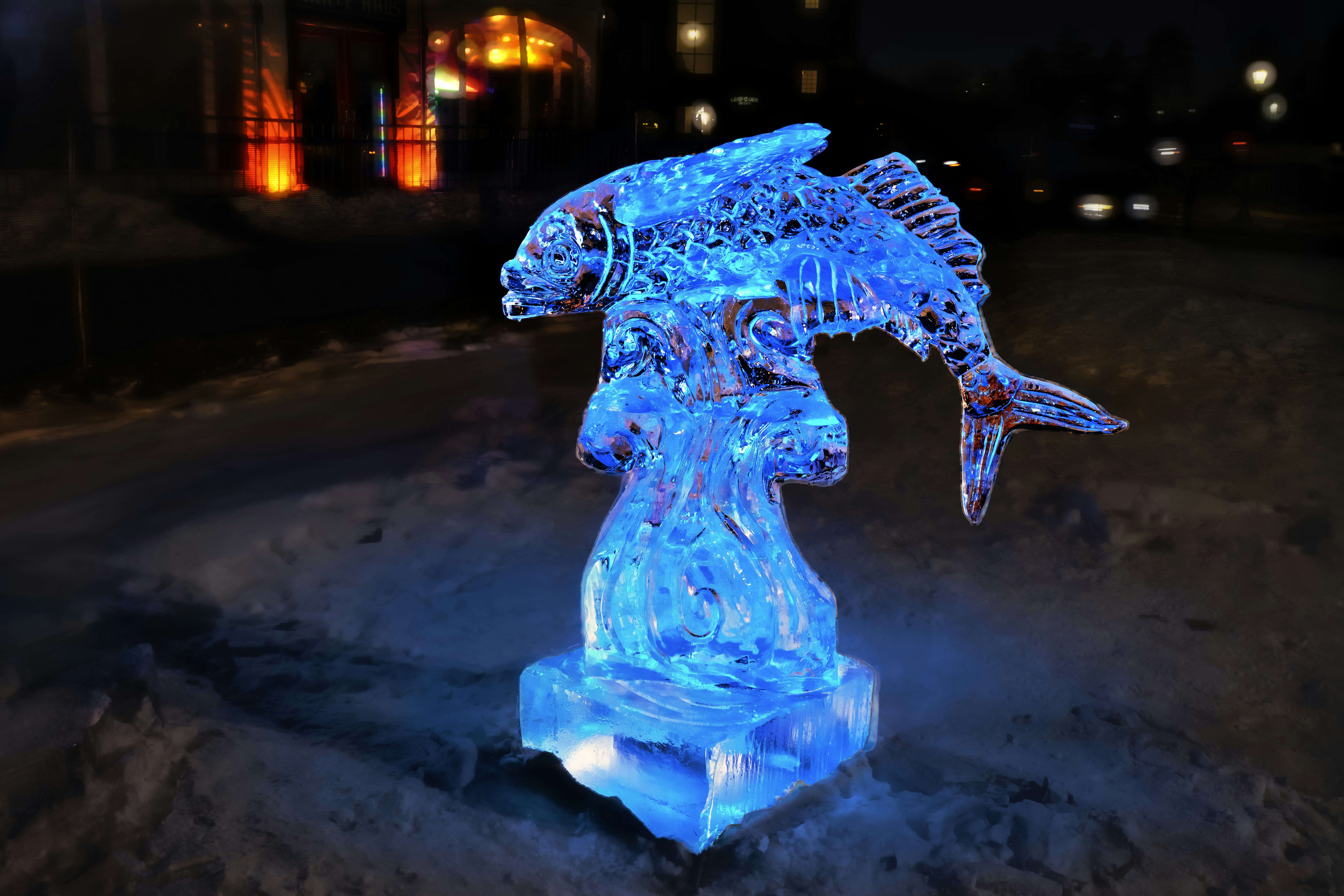 Una escultura de hielo azul brillante de un pez por la noche