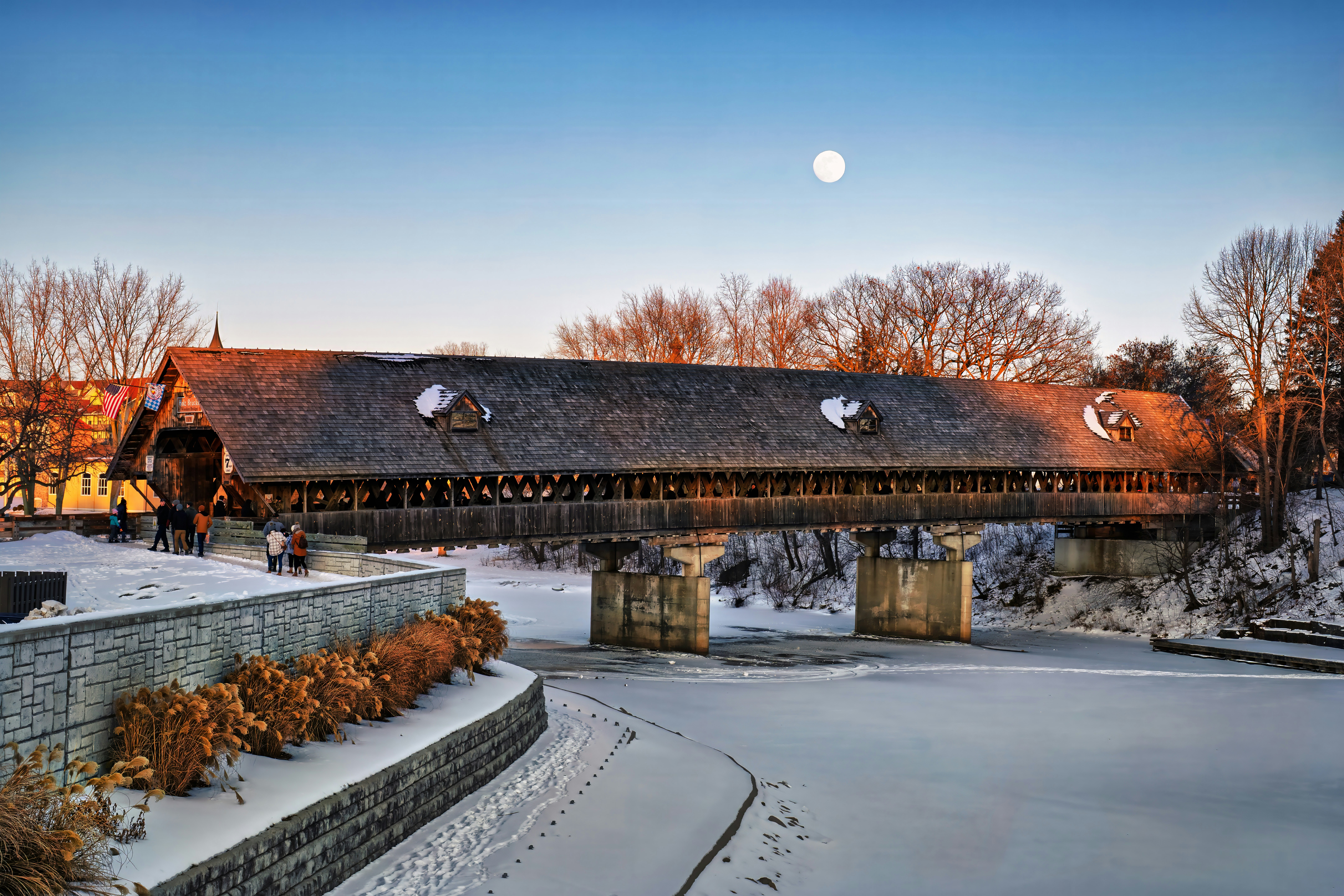 Covered wooden bridge over a frozen river in winter