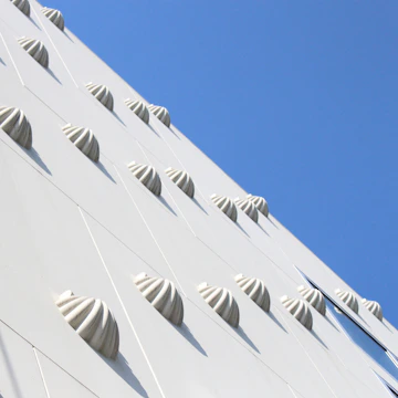 Modern white building facade with patterned details and blue sky.