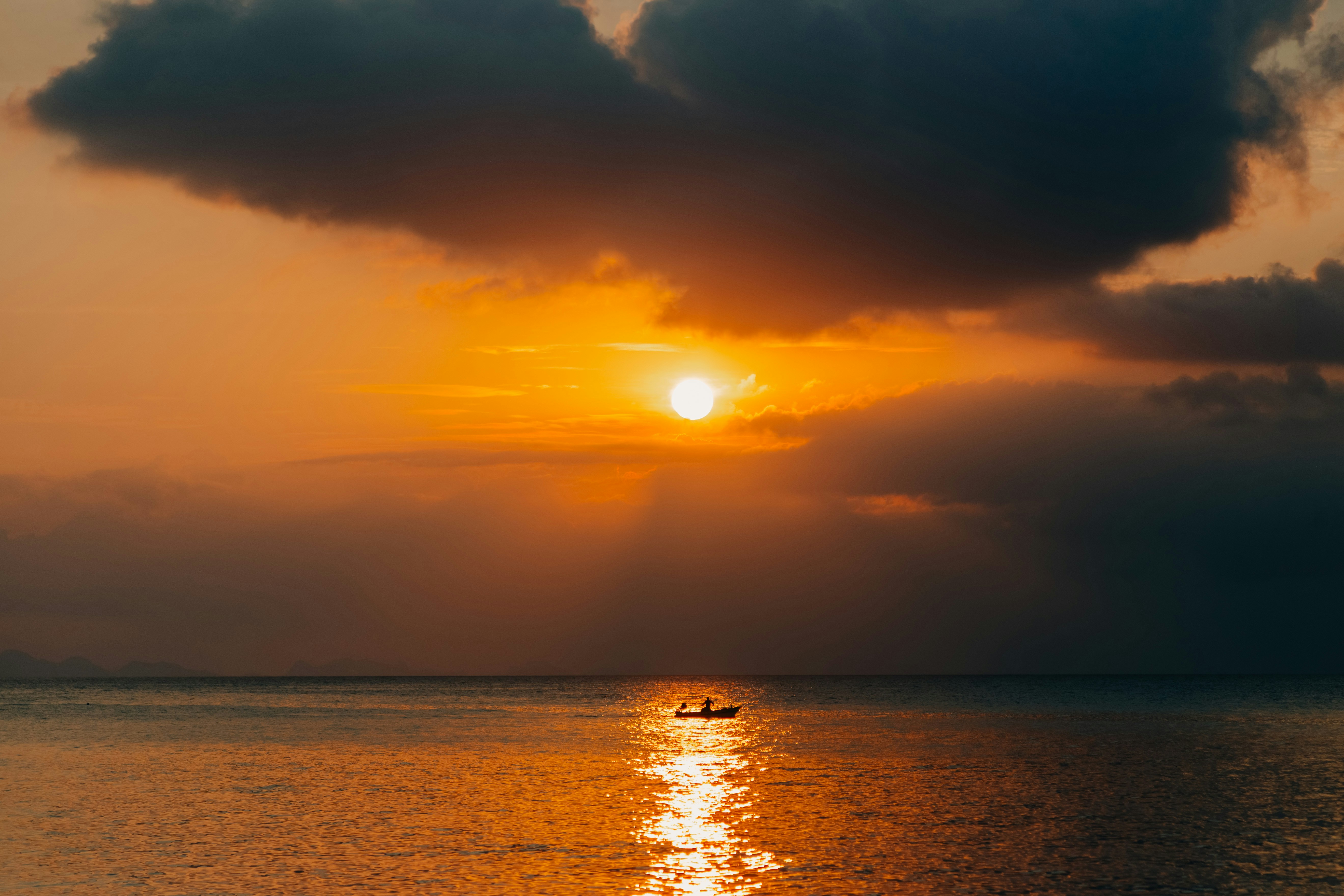 Small boat on calm sea at sunset