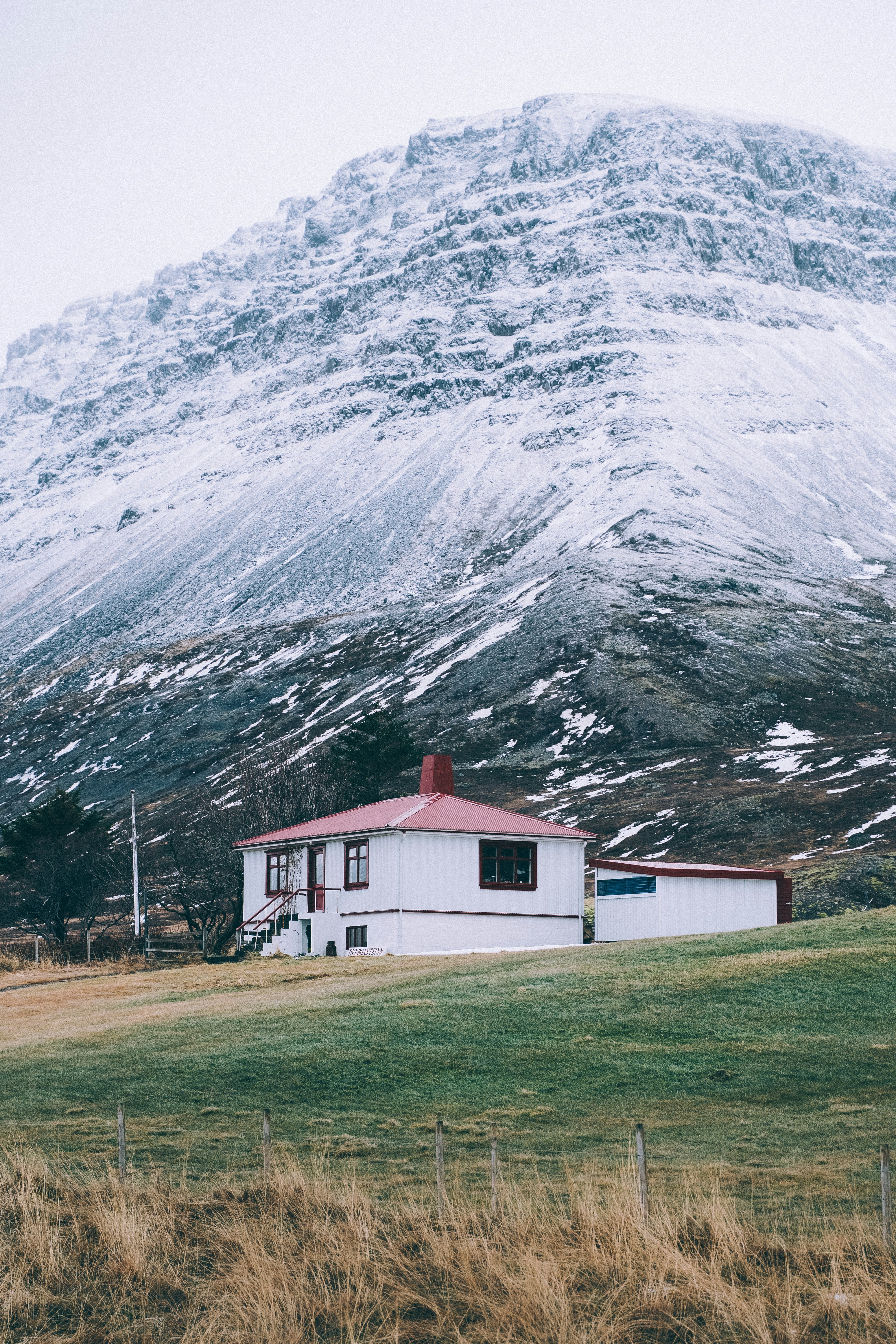 Weißes Haus mit rotem Dach unterhalb des verschneiten Berges