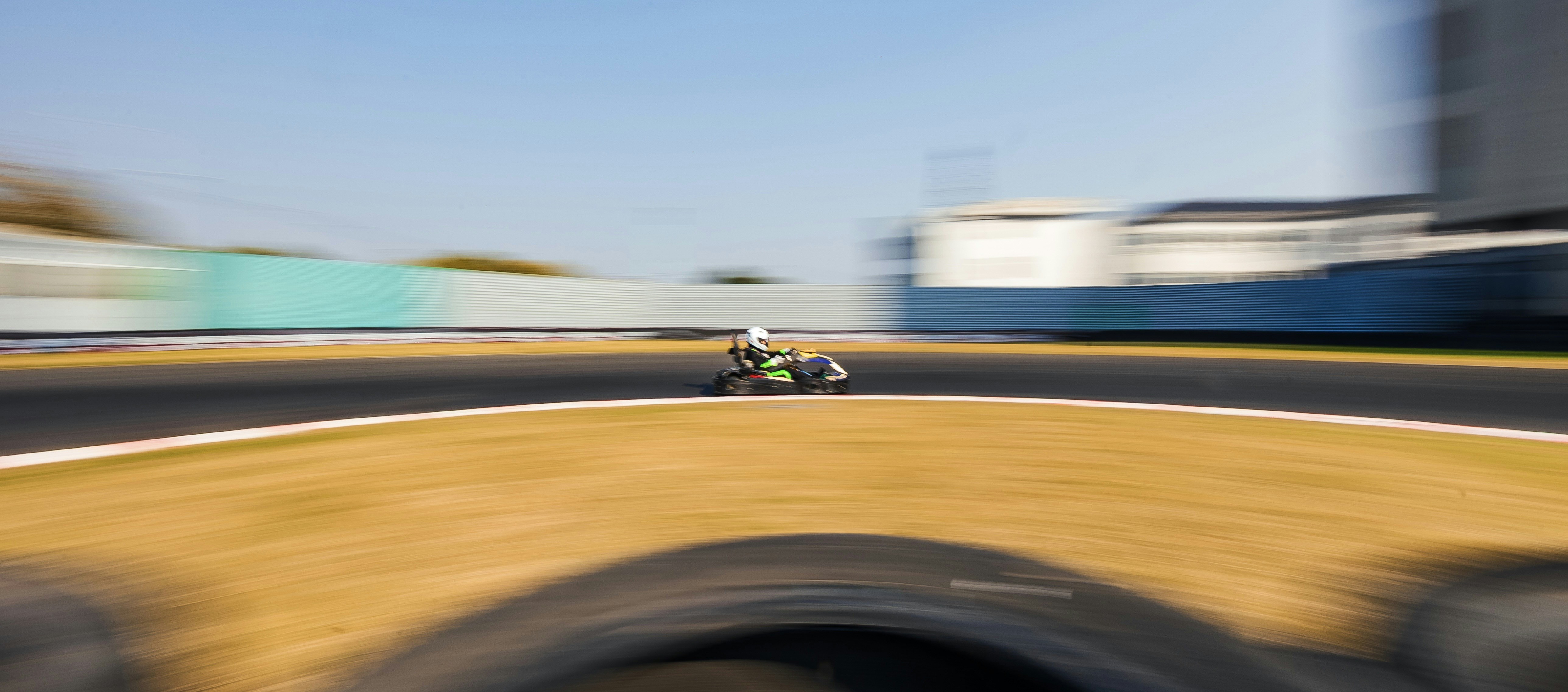 Go-kart racing on a sunny track with motion blur.