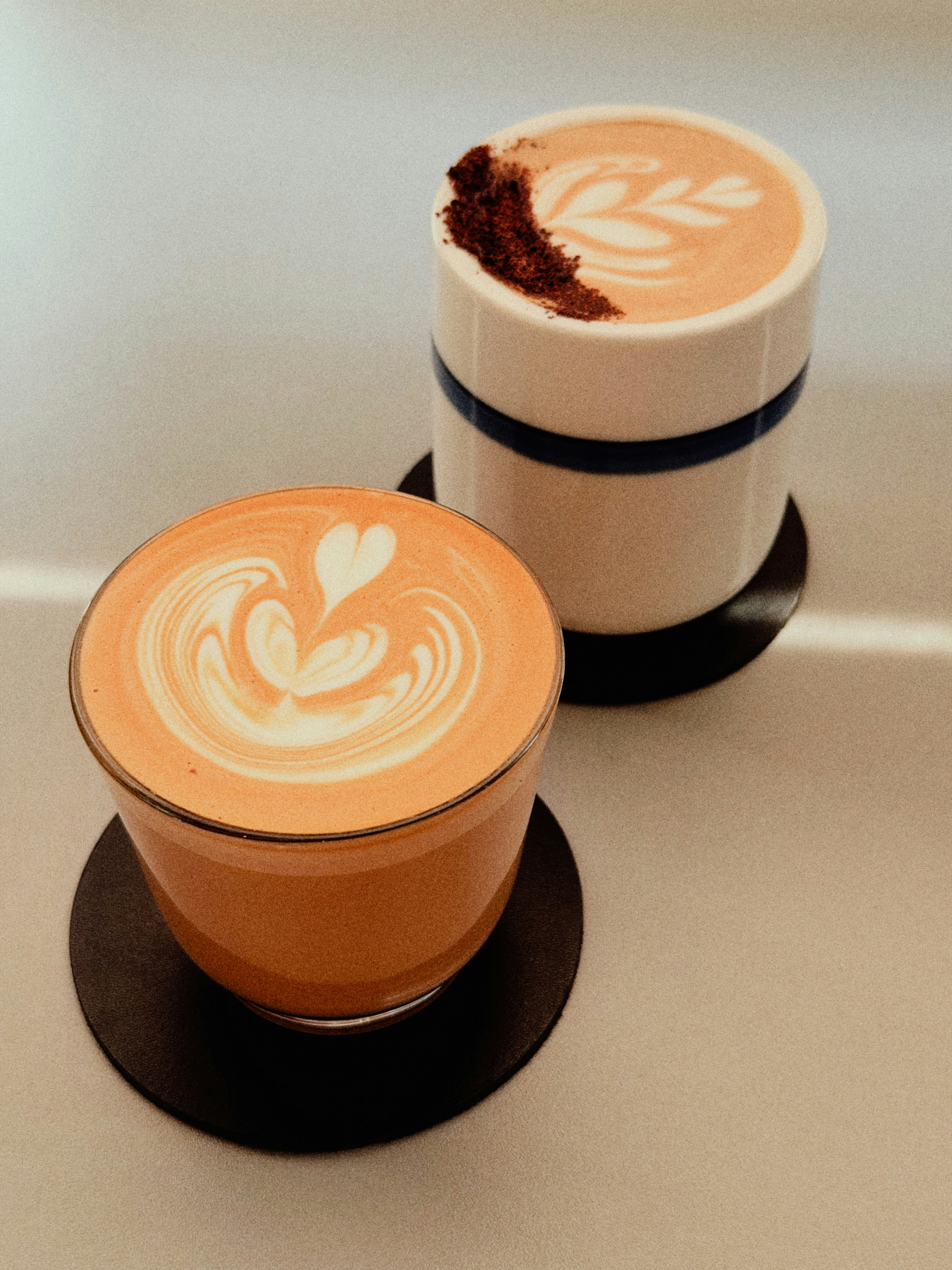 Two cups of latte art coffee on coasters
