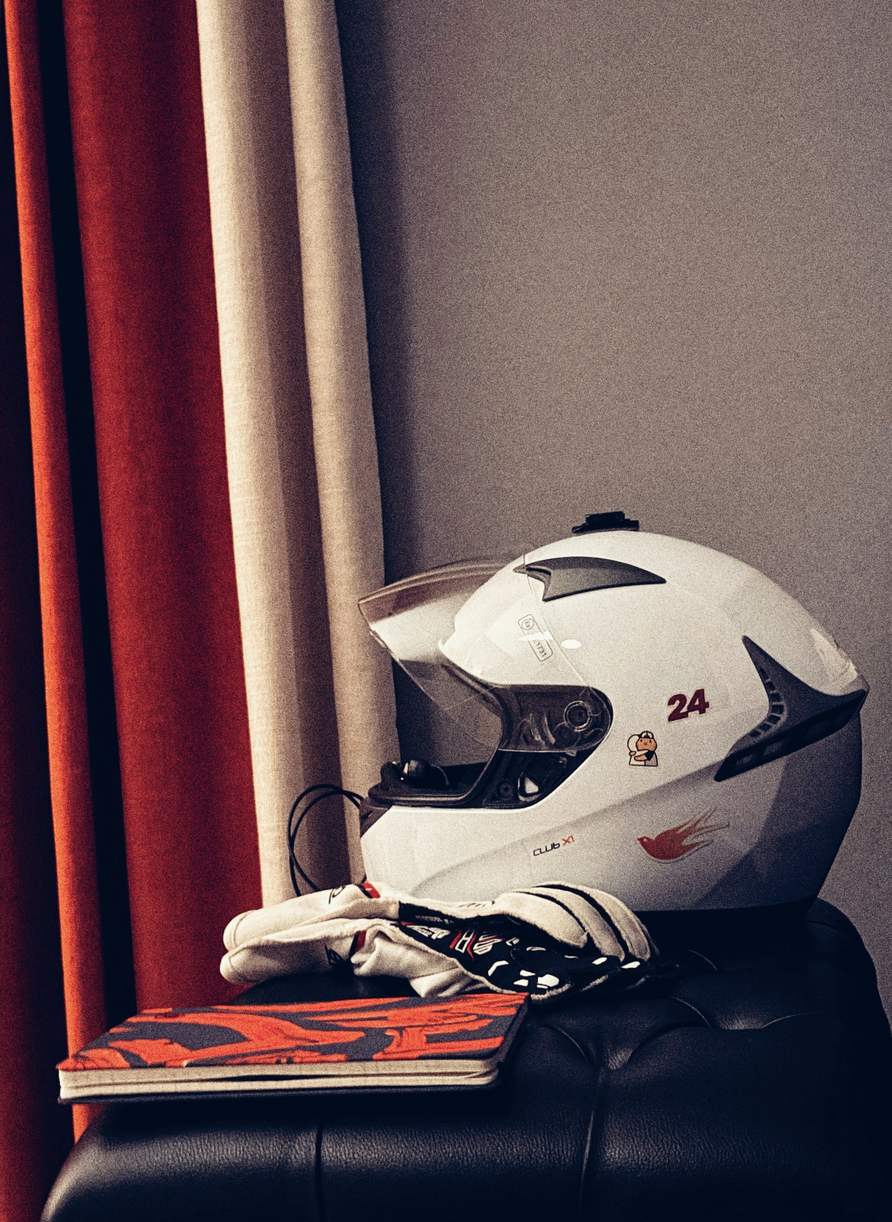 Weißer Motorradhelm mit Handschuhen und Buch.