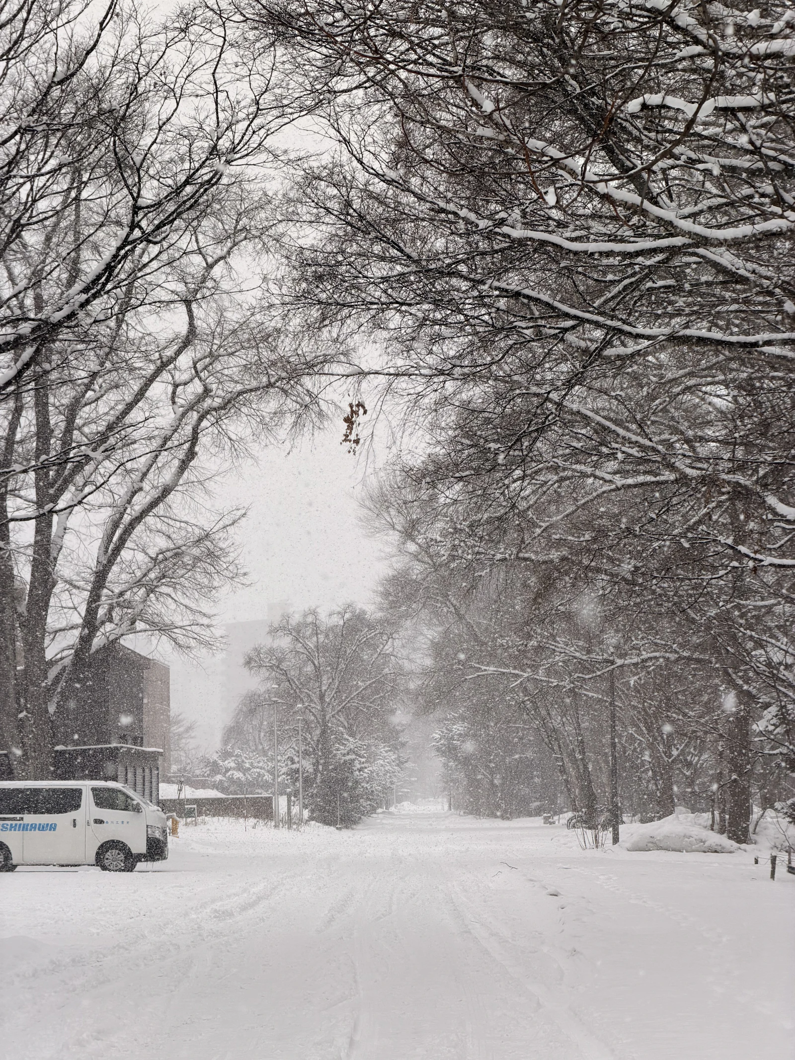 A vehicle travels through a snowy Japanese landscape