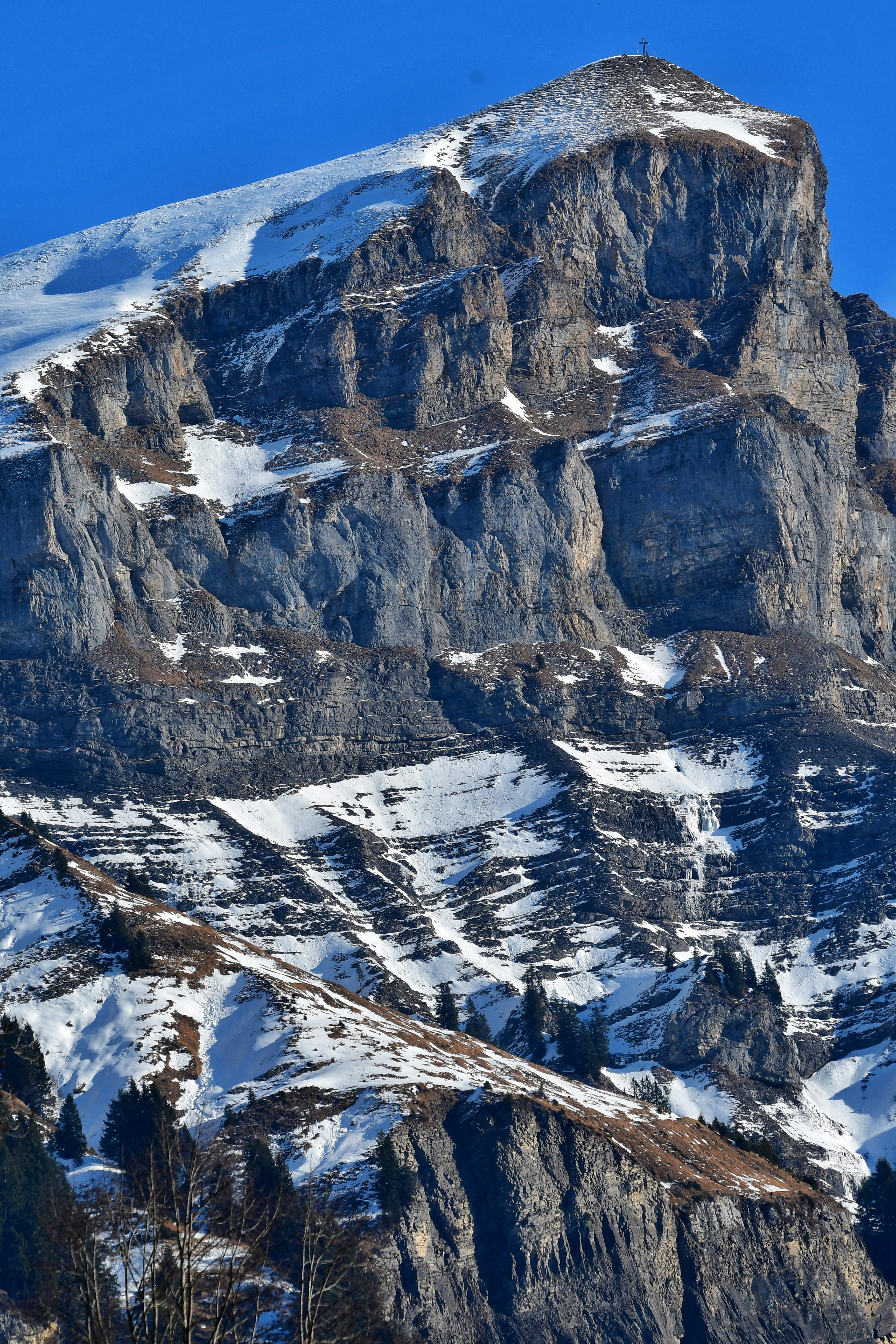 Rugged mountain peak with snow and trees