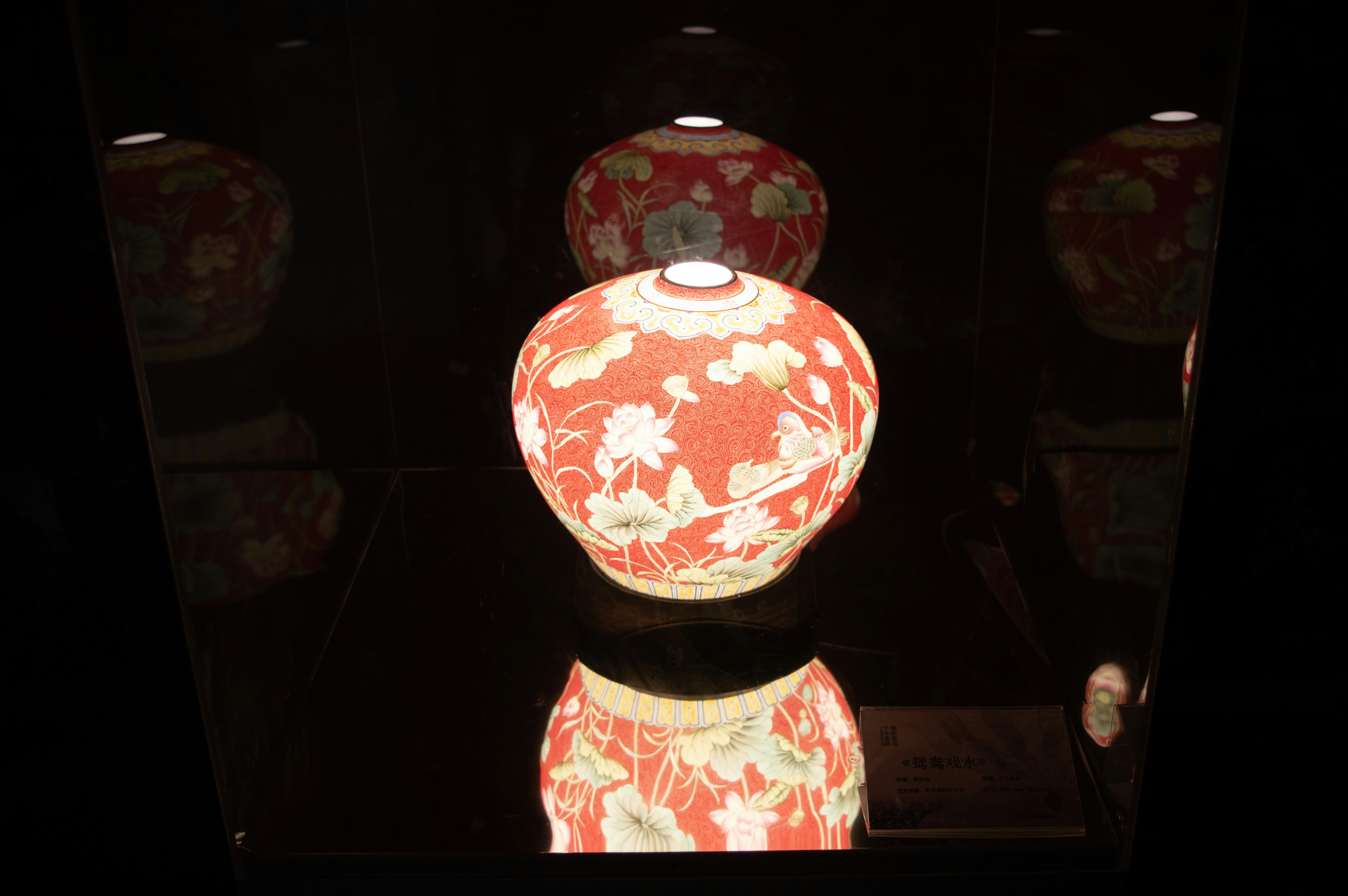 Zwei kunstvoll verzierte rote Vasen mit Blumenmustern sind ausgestellt.