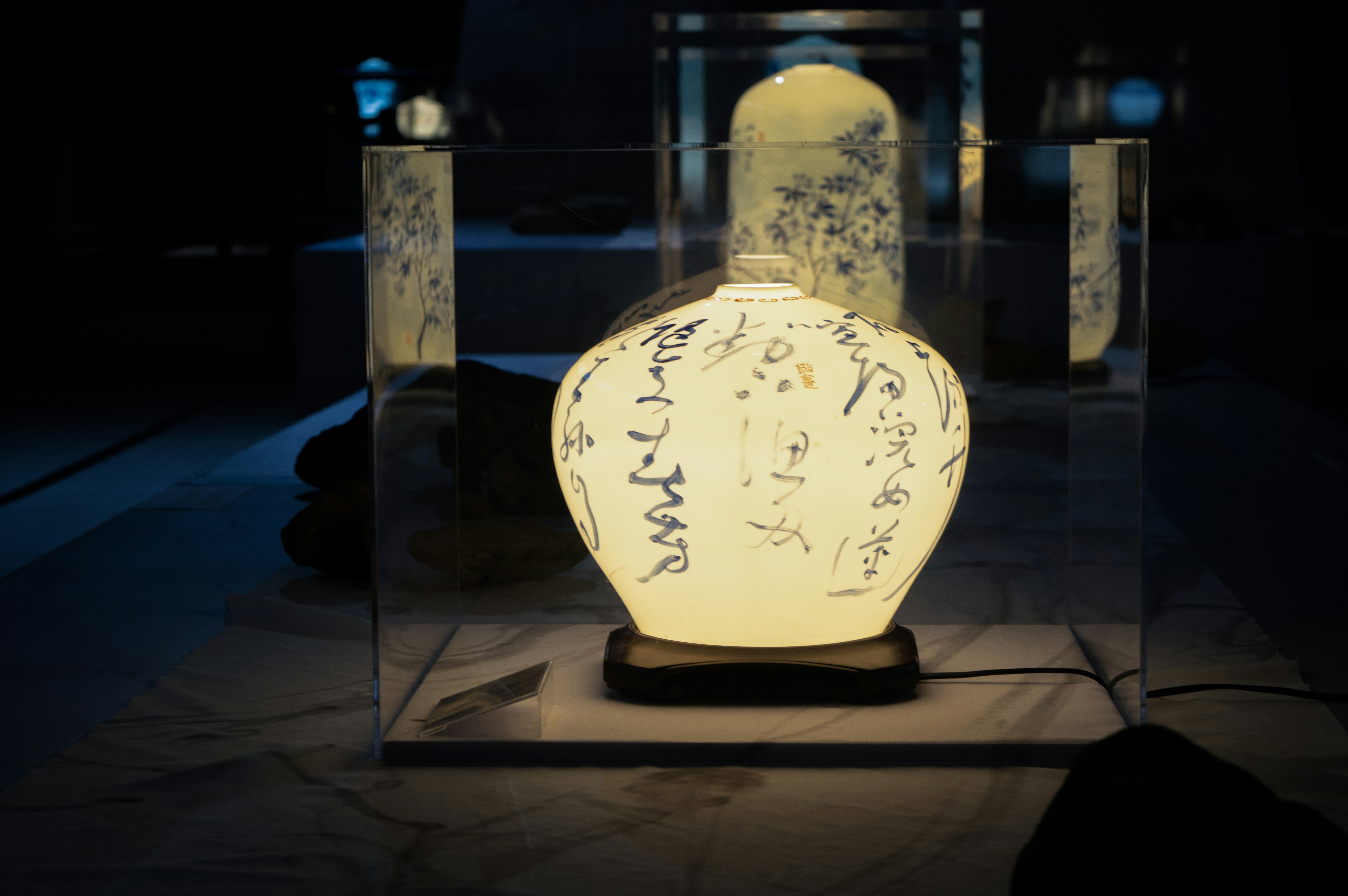 A glowing ceramic vase with calligraphy in a display.