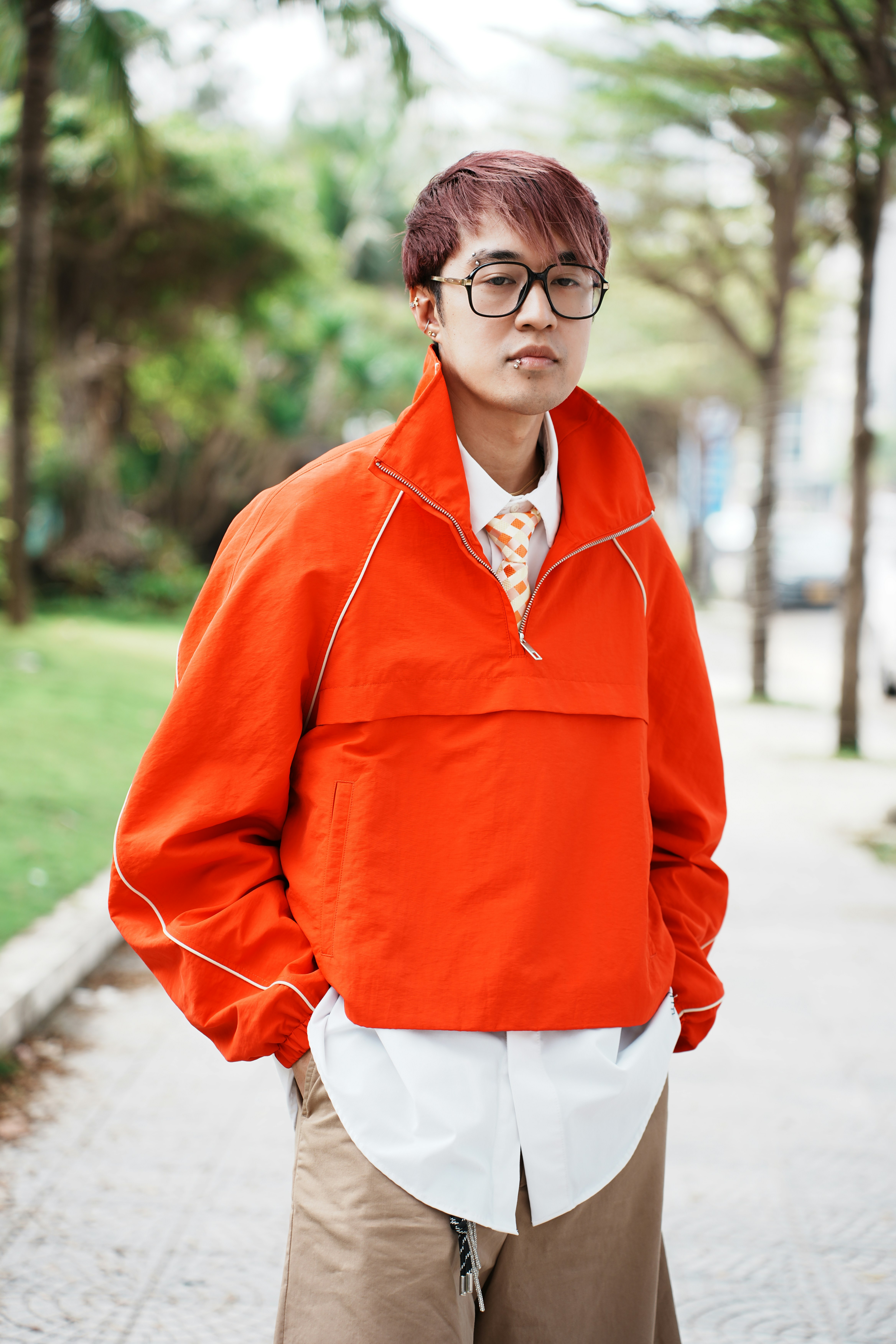 Young man in orange jacket and glasses outdoors