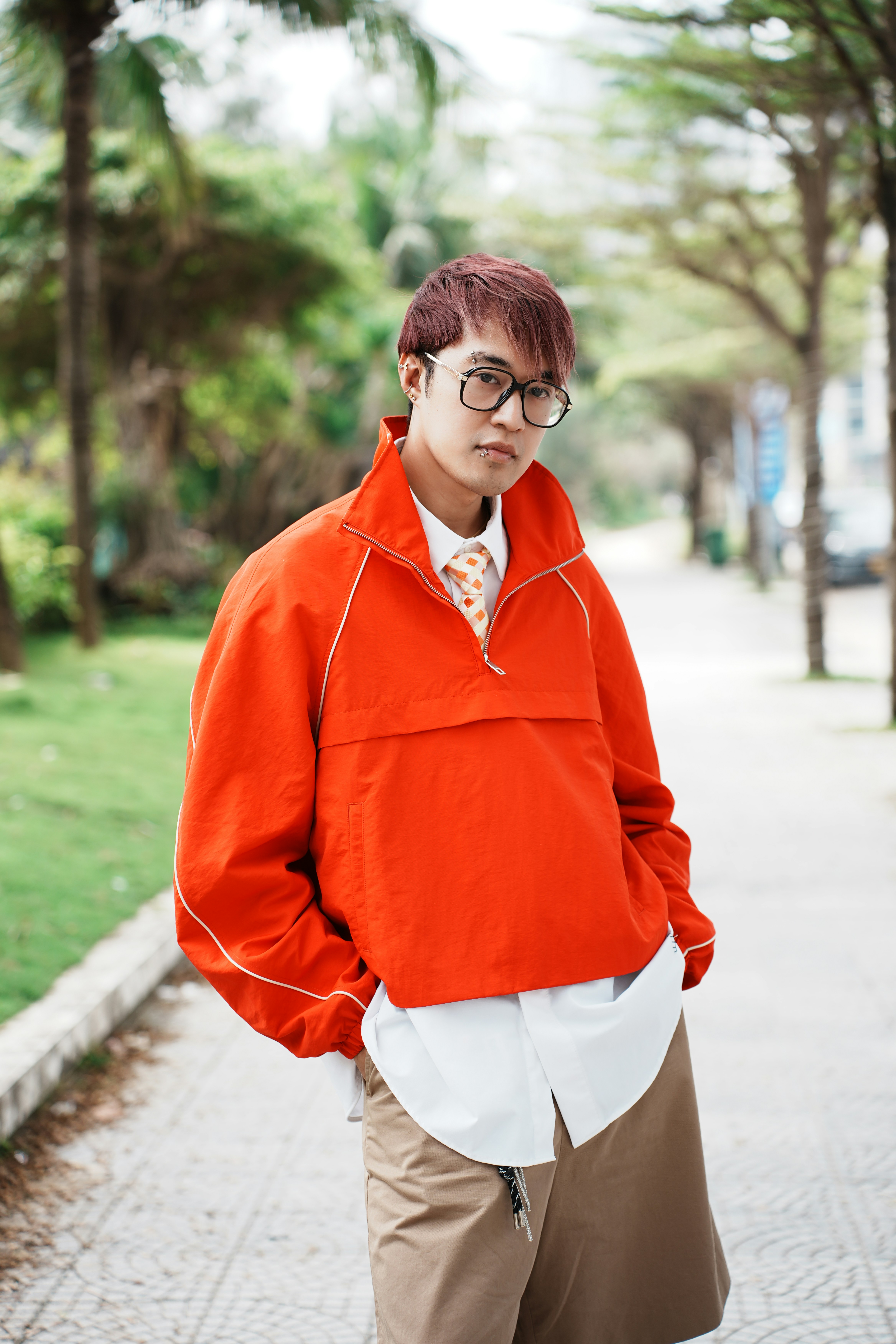 Young man in orange jacket and glasses outdoors