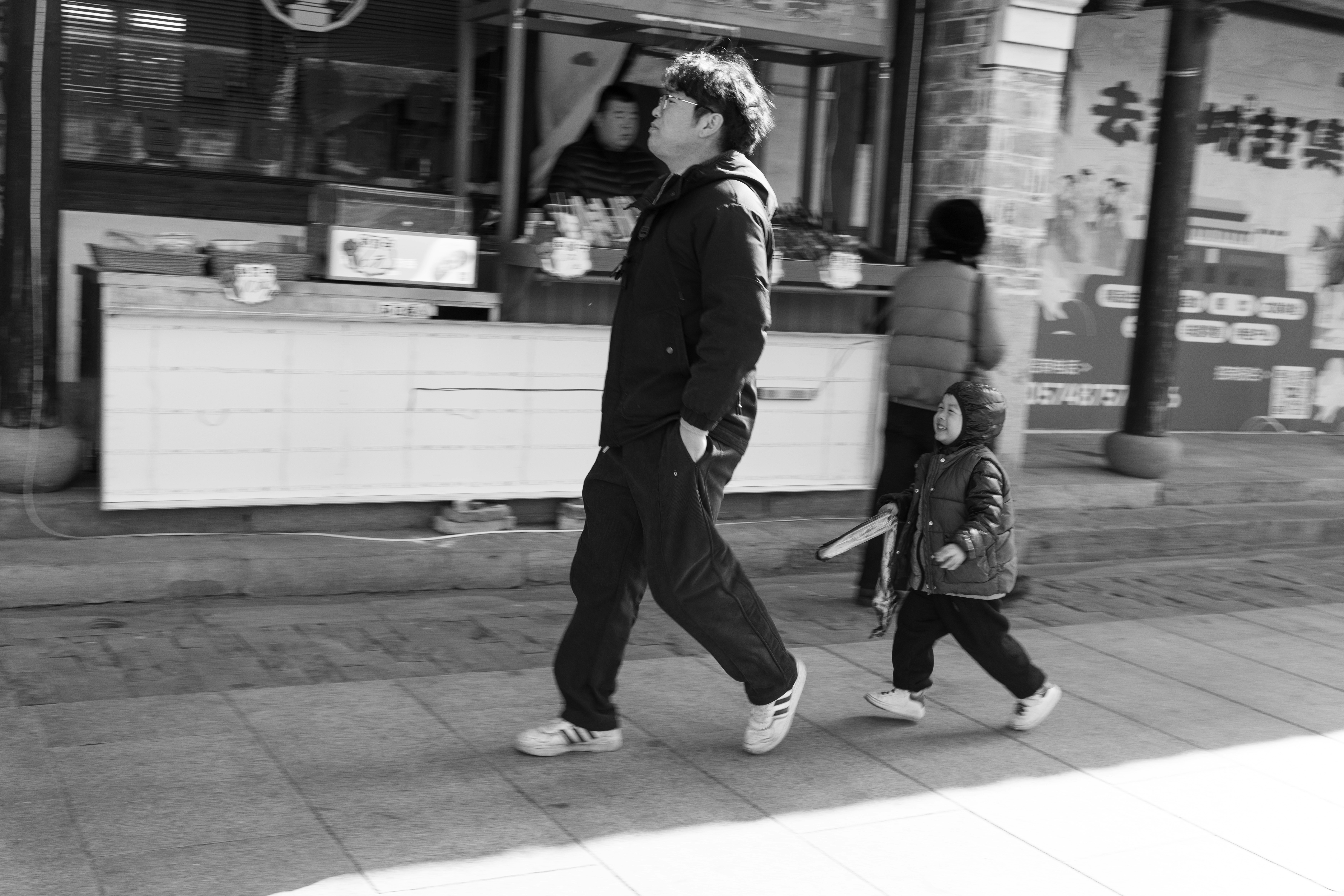 Man and child walk on a sidewalk.