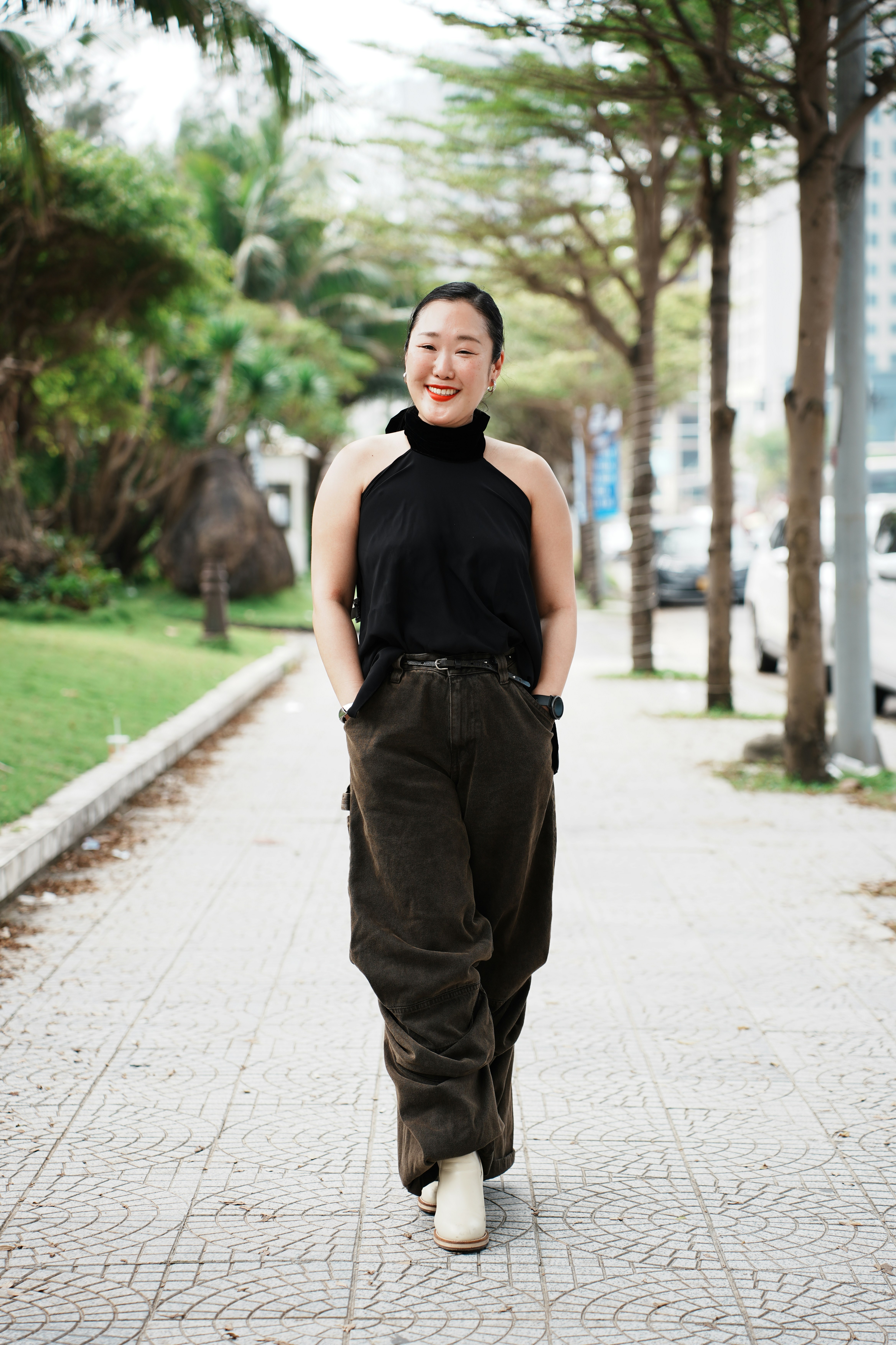 A smiling woman walks down a sidewalk.