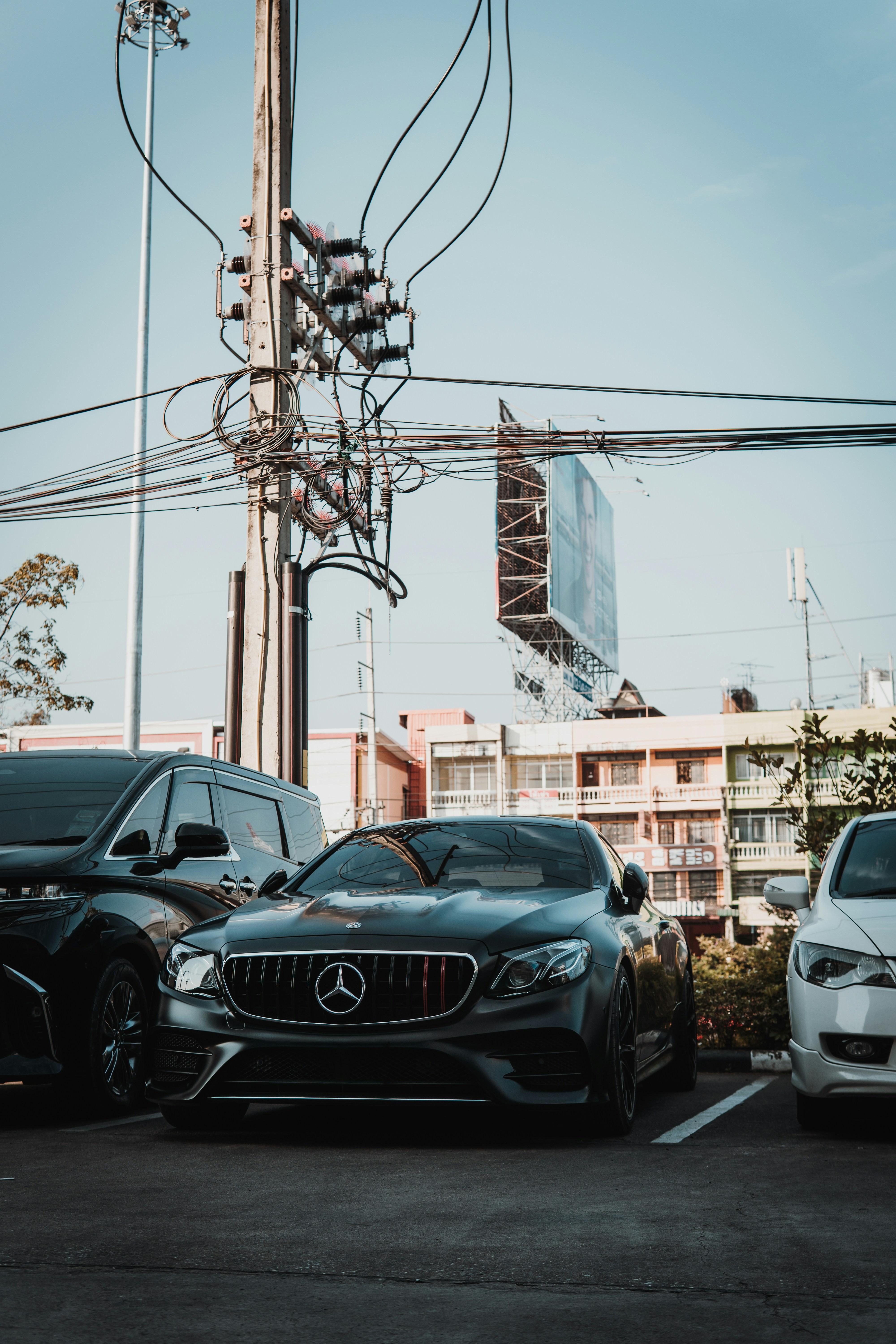 A black mercedes-benz parked with other cars.