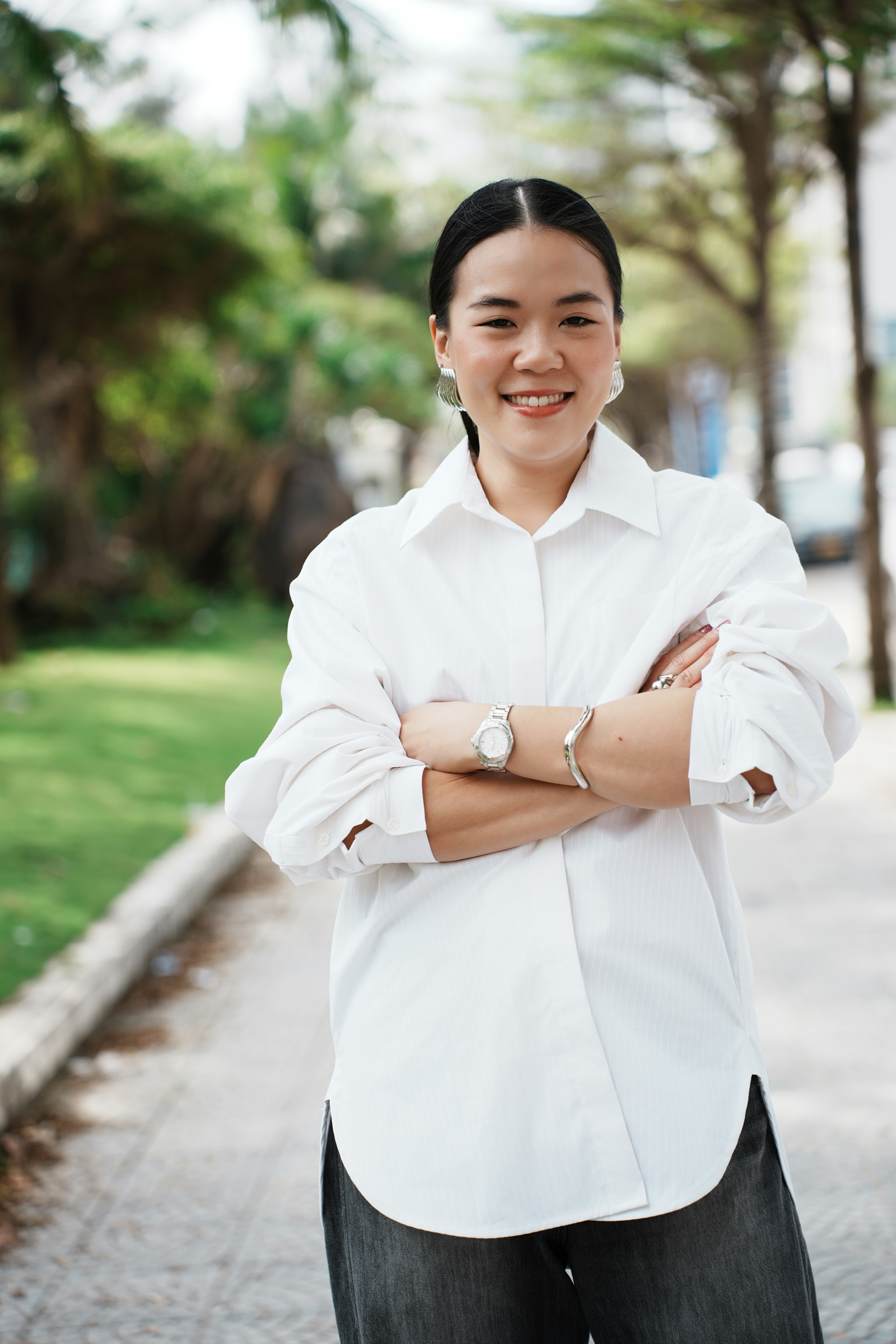 Una mujer sonriente con camisa blanca y brazos cruzados.