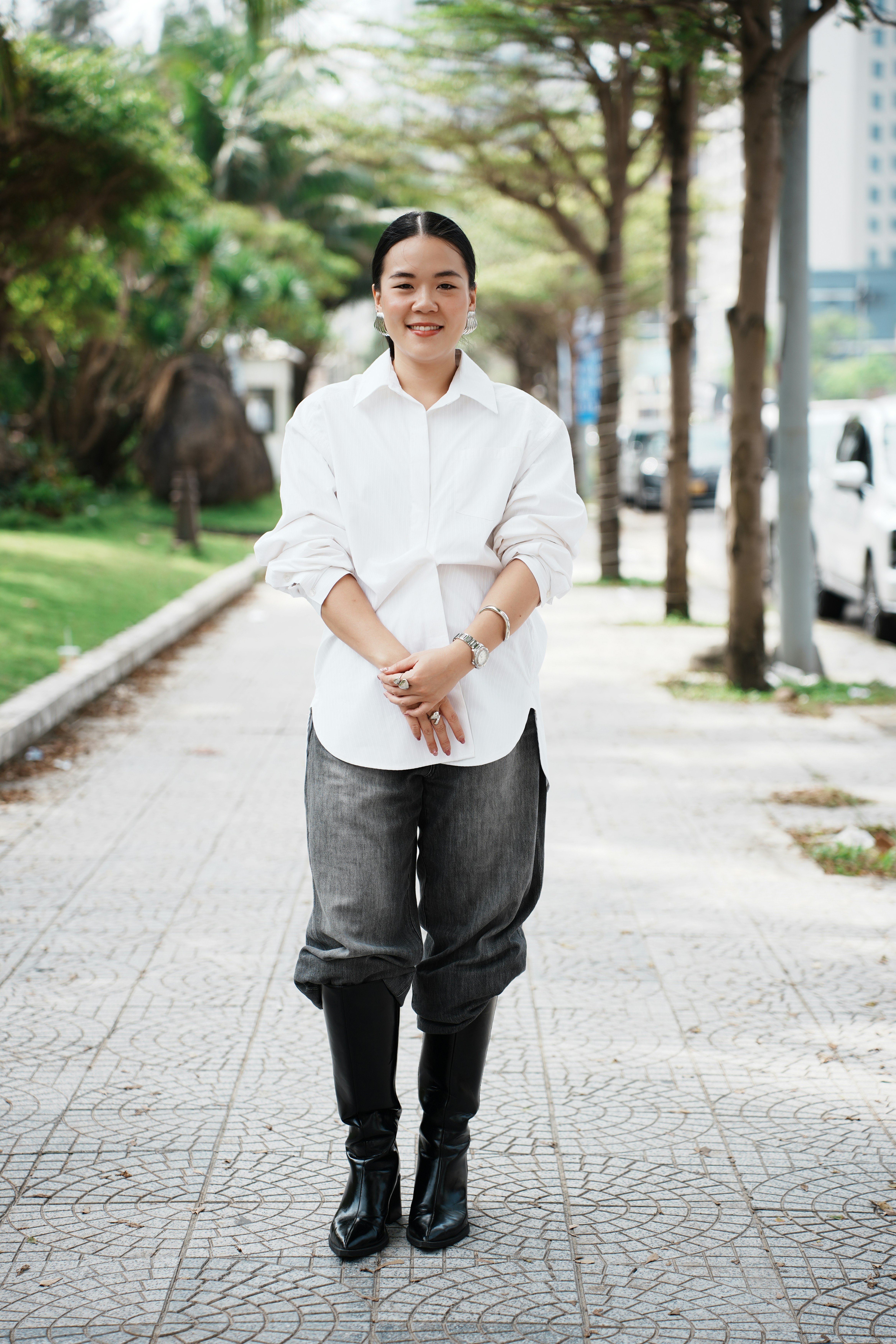 Woman in white shirt and black boots walks on sidewalk
