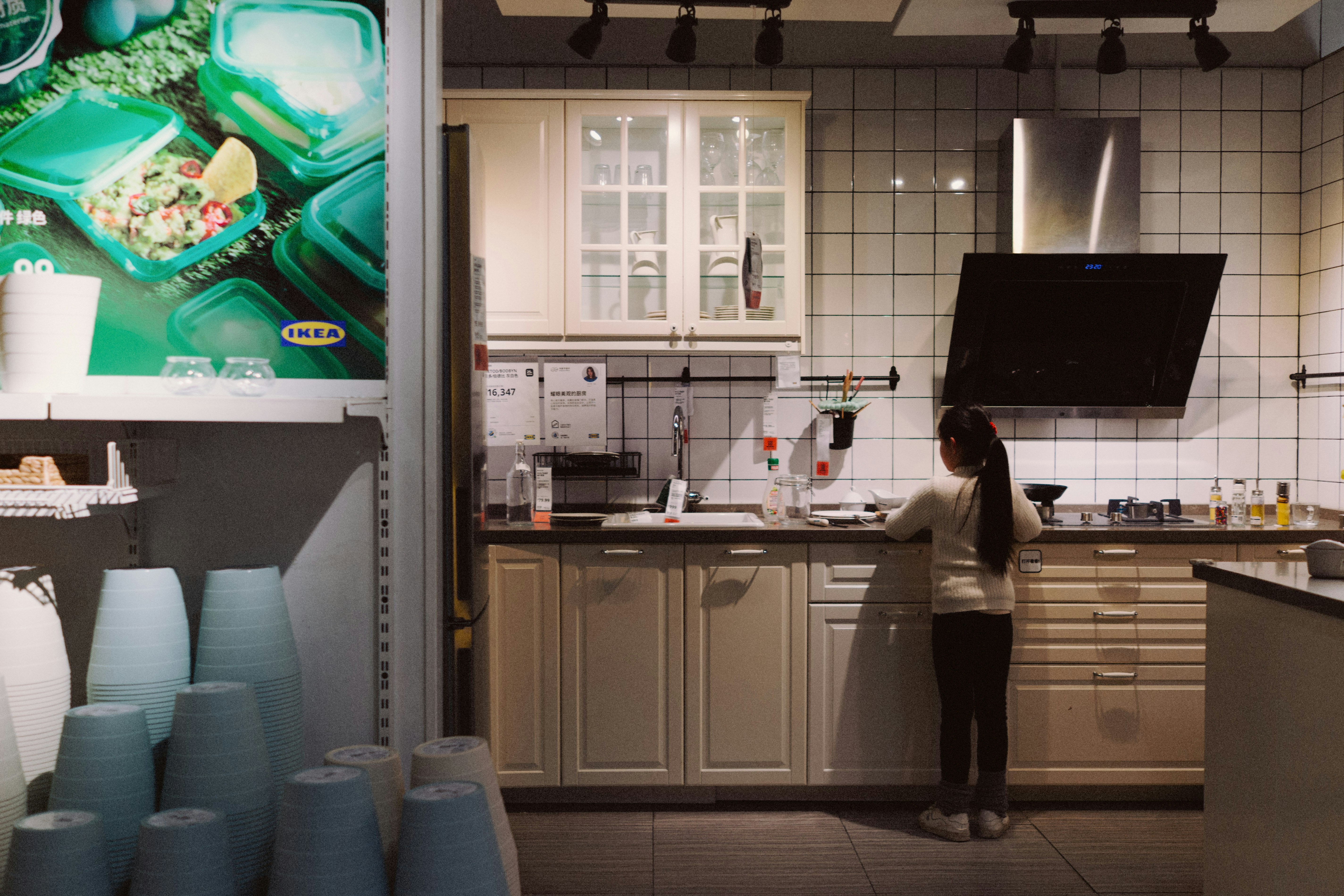 A girl stands in a modern kitchen display.