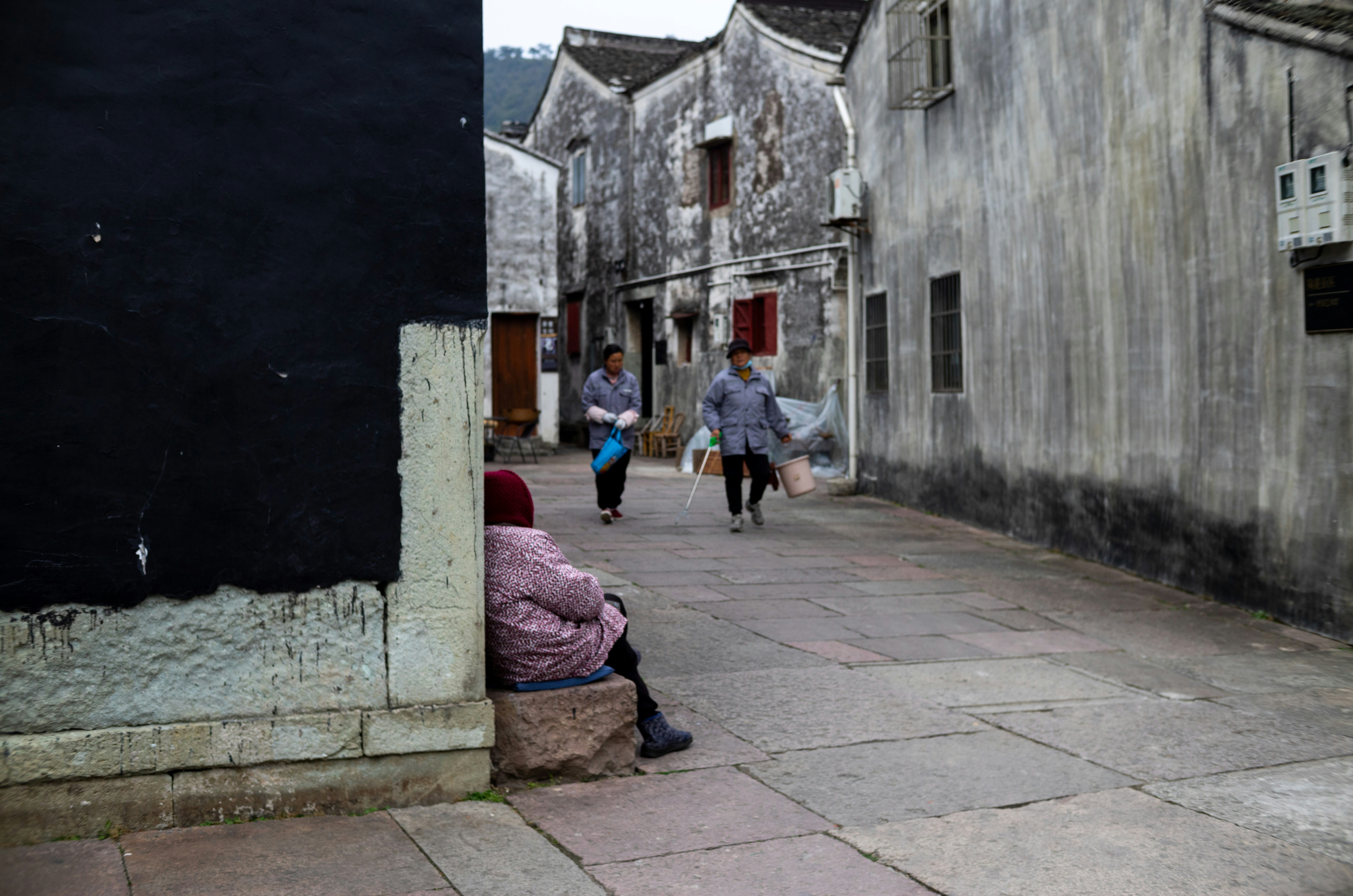 People walking down a narrow, old street in china.