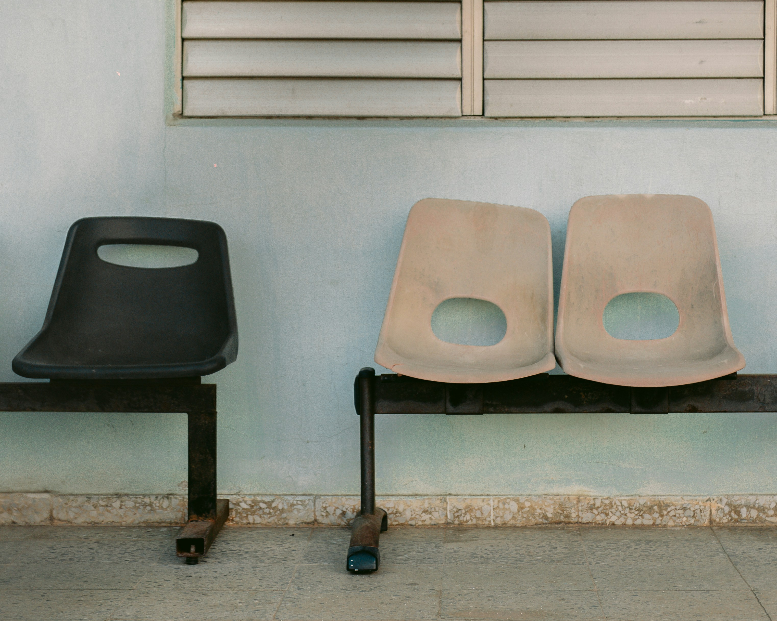 Three chairs sit on a bench against a wall.