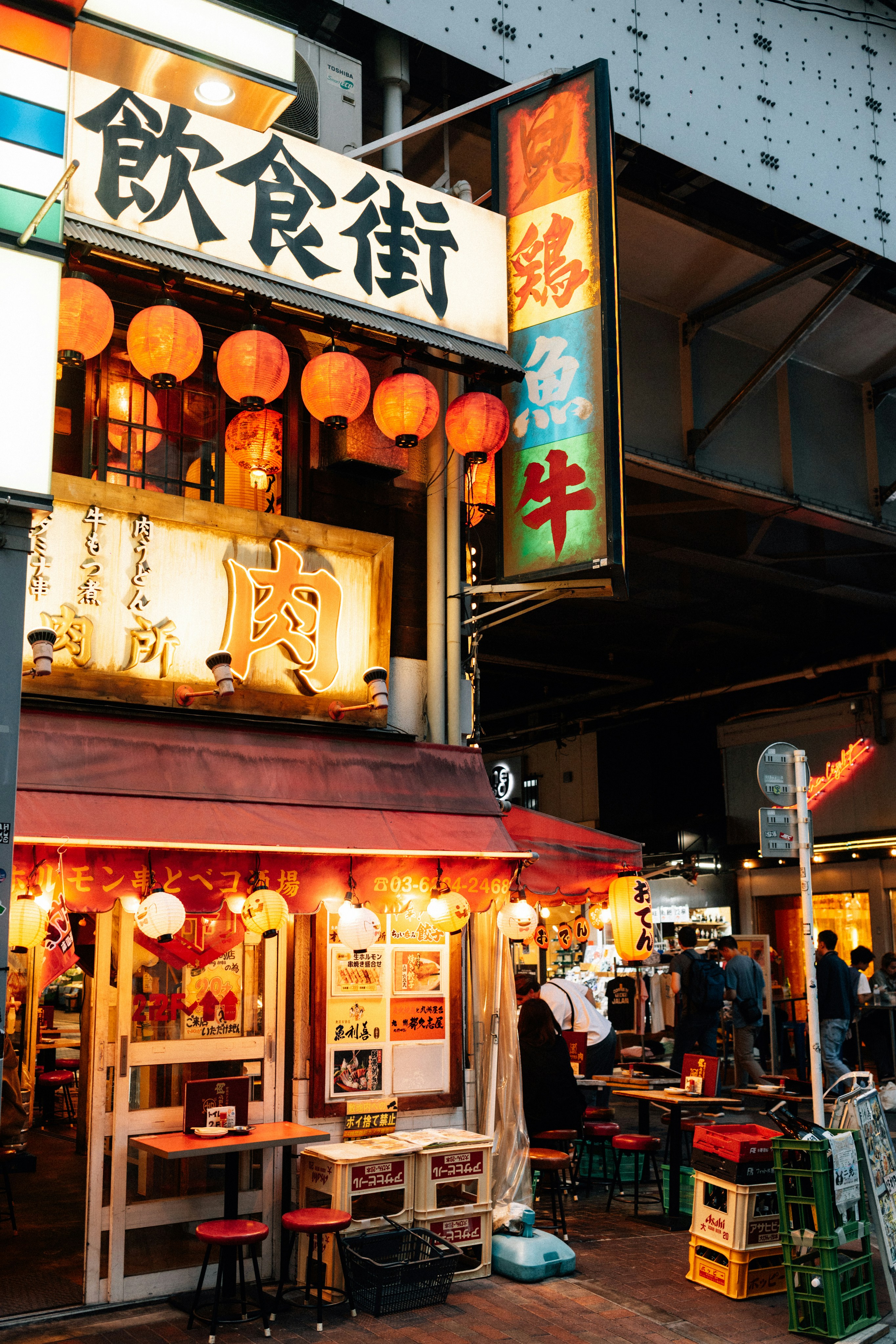 Photo of Japanese restaurant with red lanterns and signs by Tsuyoshi Kozu