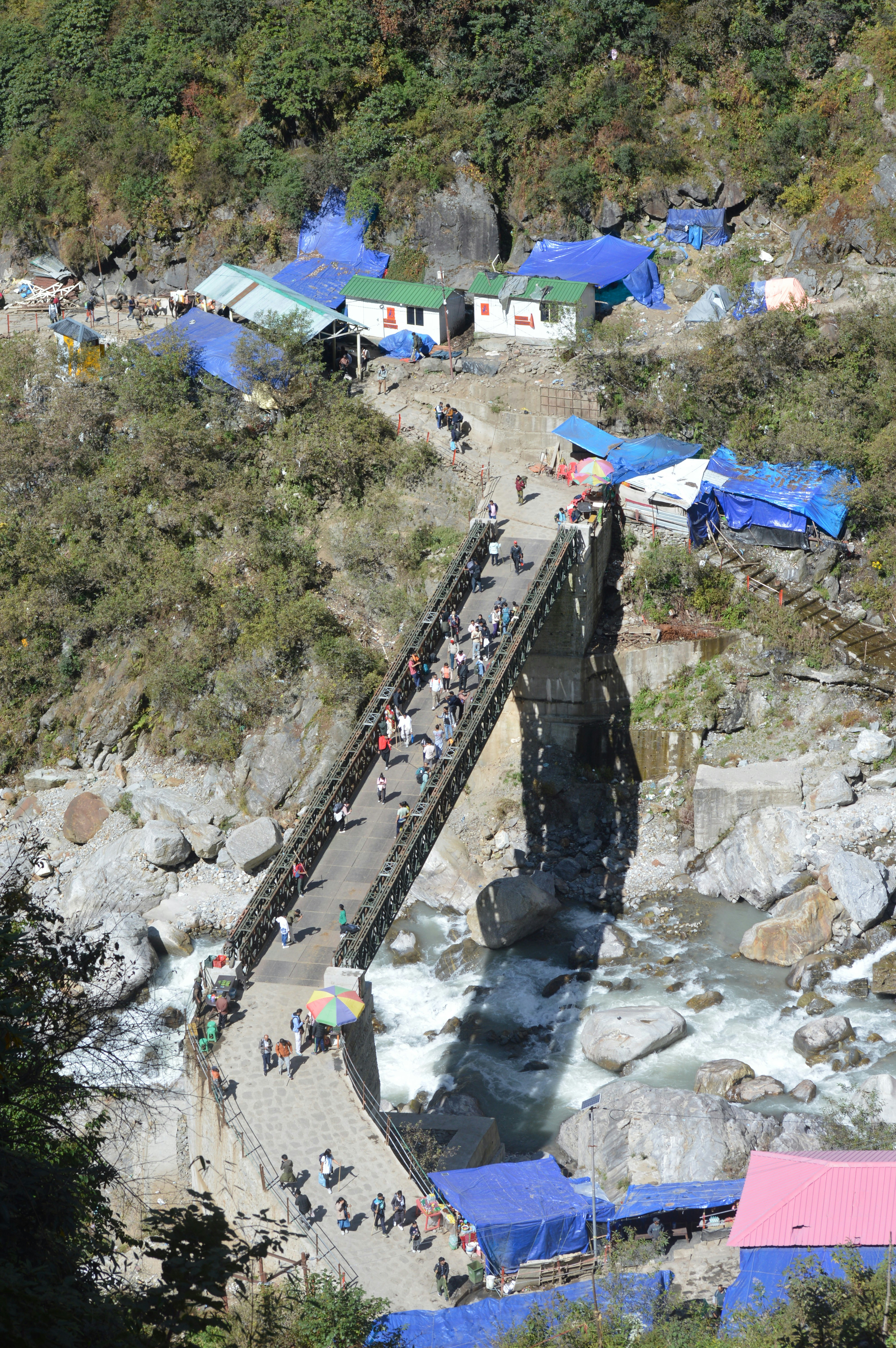People crossing a bridge over a rocky river