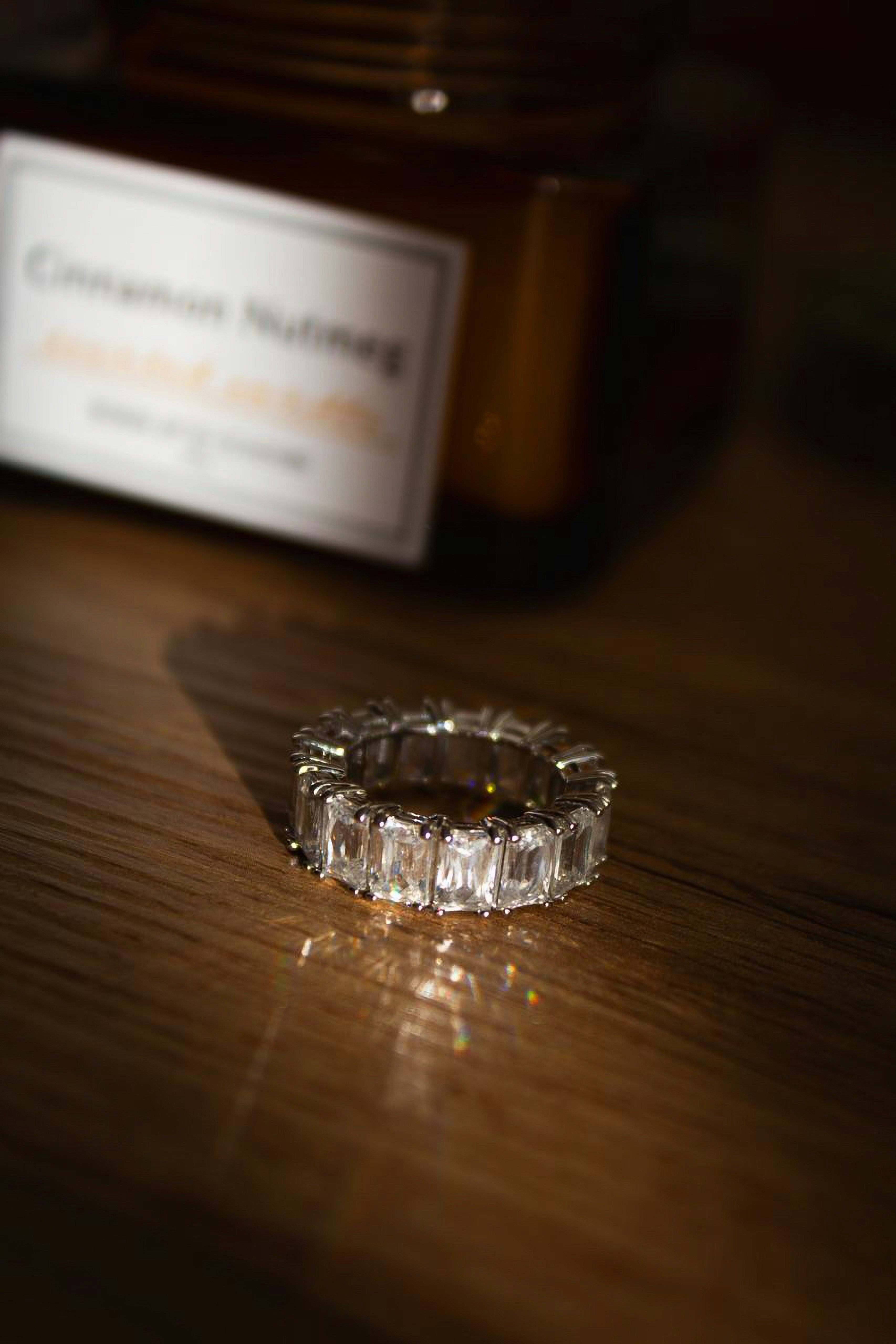 A sparkling emerald-cut diamond ring on a wooden surface.