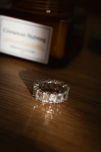 A sparkling emerald-cut diamond ring on a wooden surface.