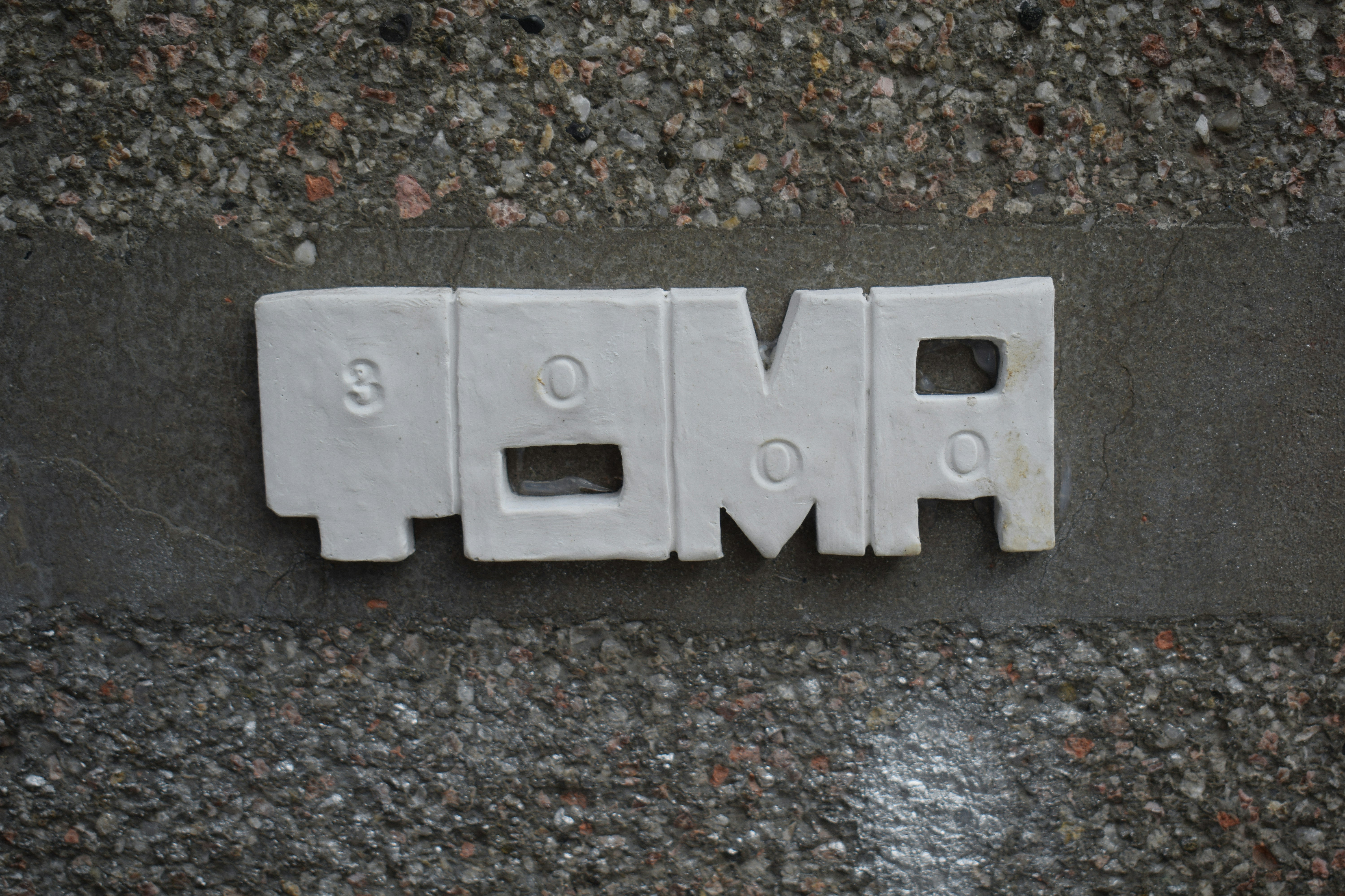 White ceramic letters spell out of focus on a wall