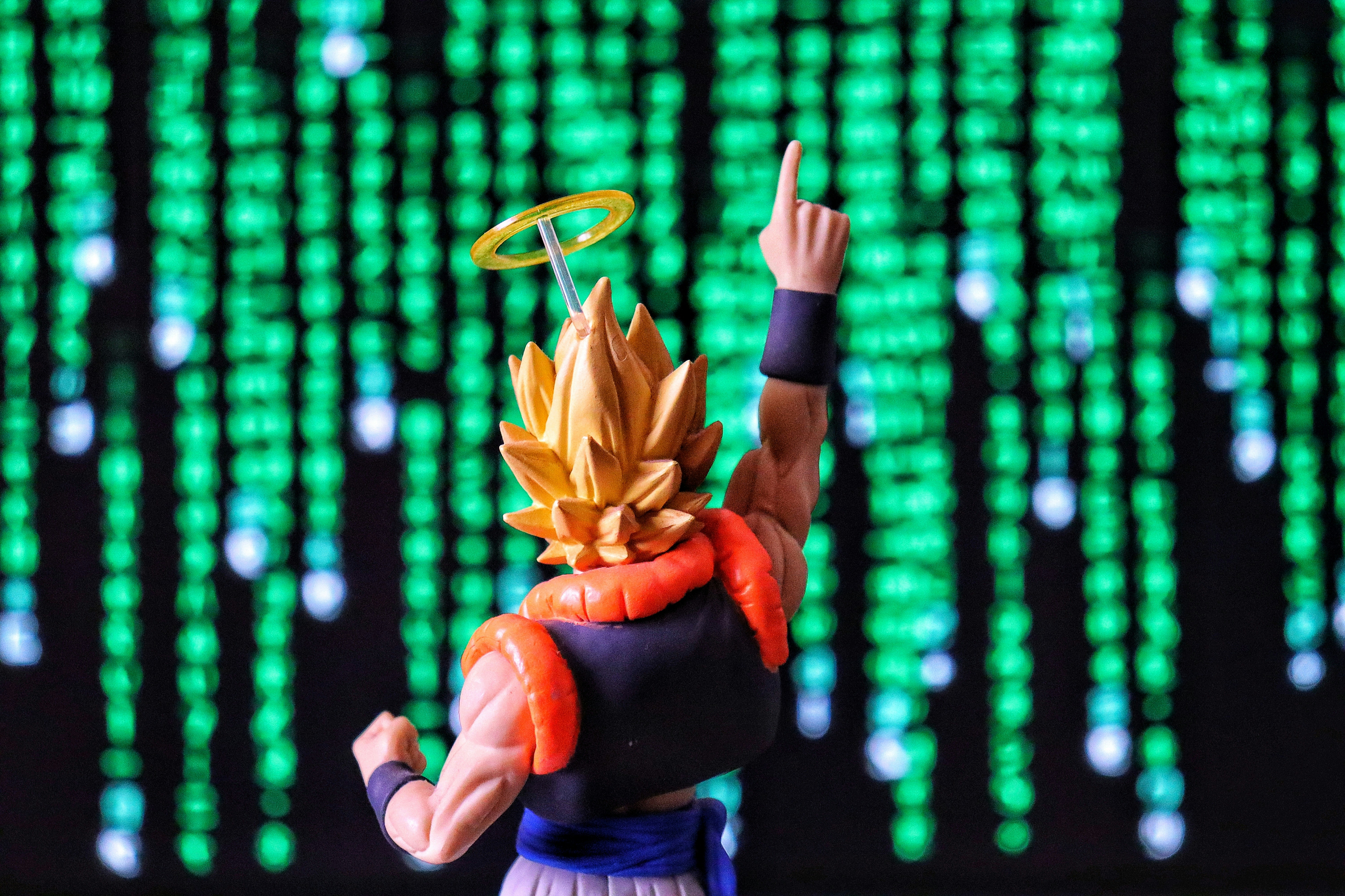 Action figure with halo pointing upwards against green digital background