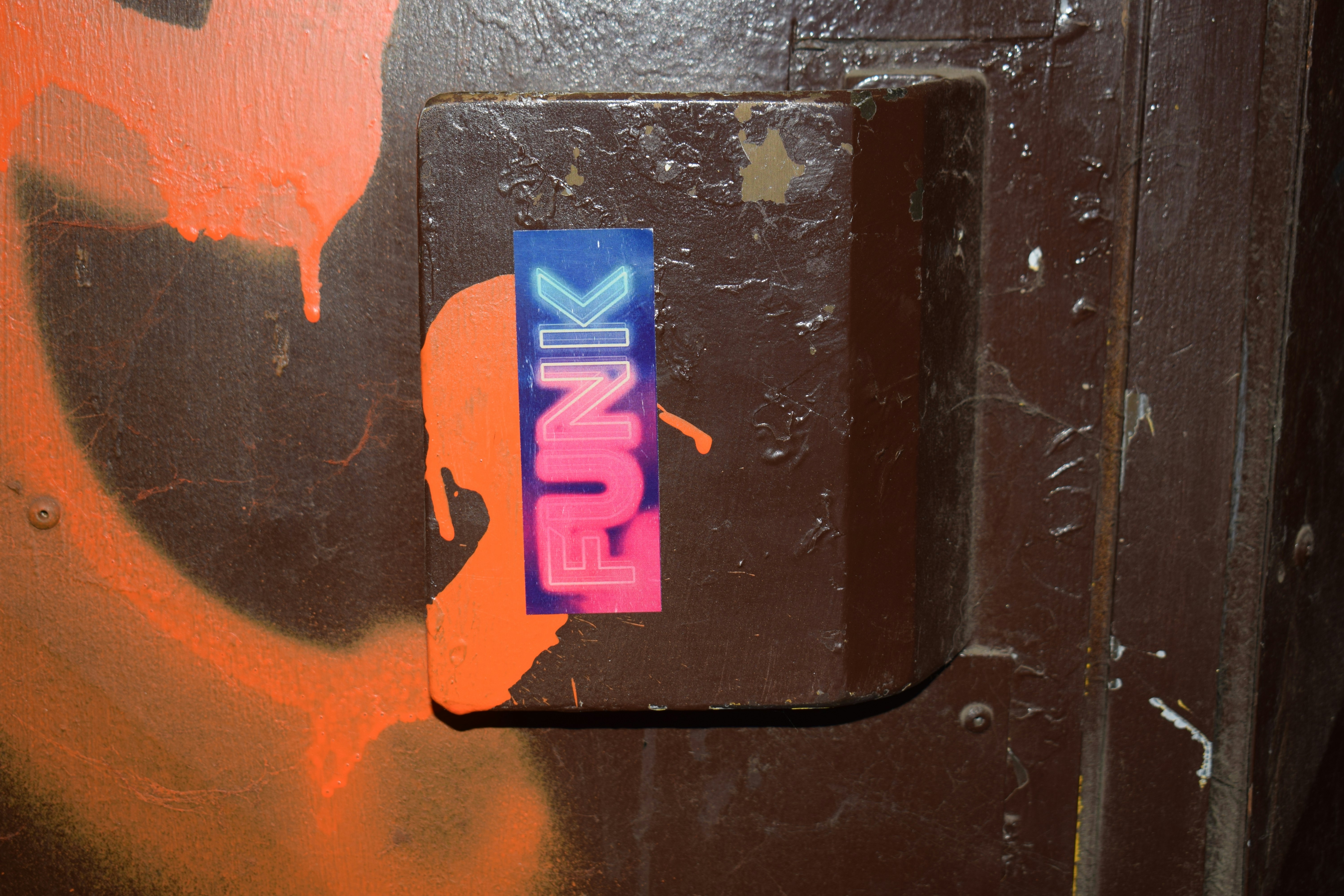 A sticker that says "funk" on a brown surface.