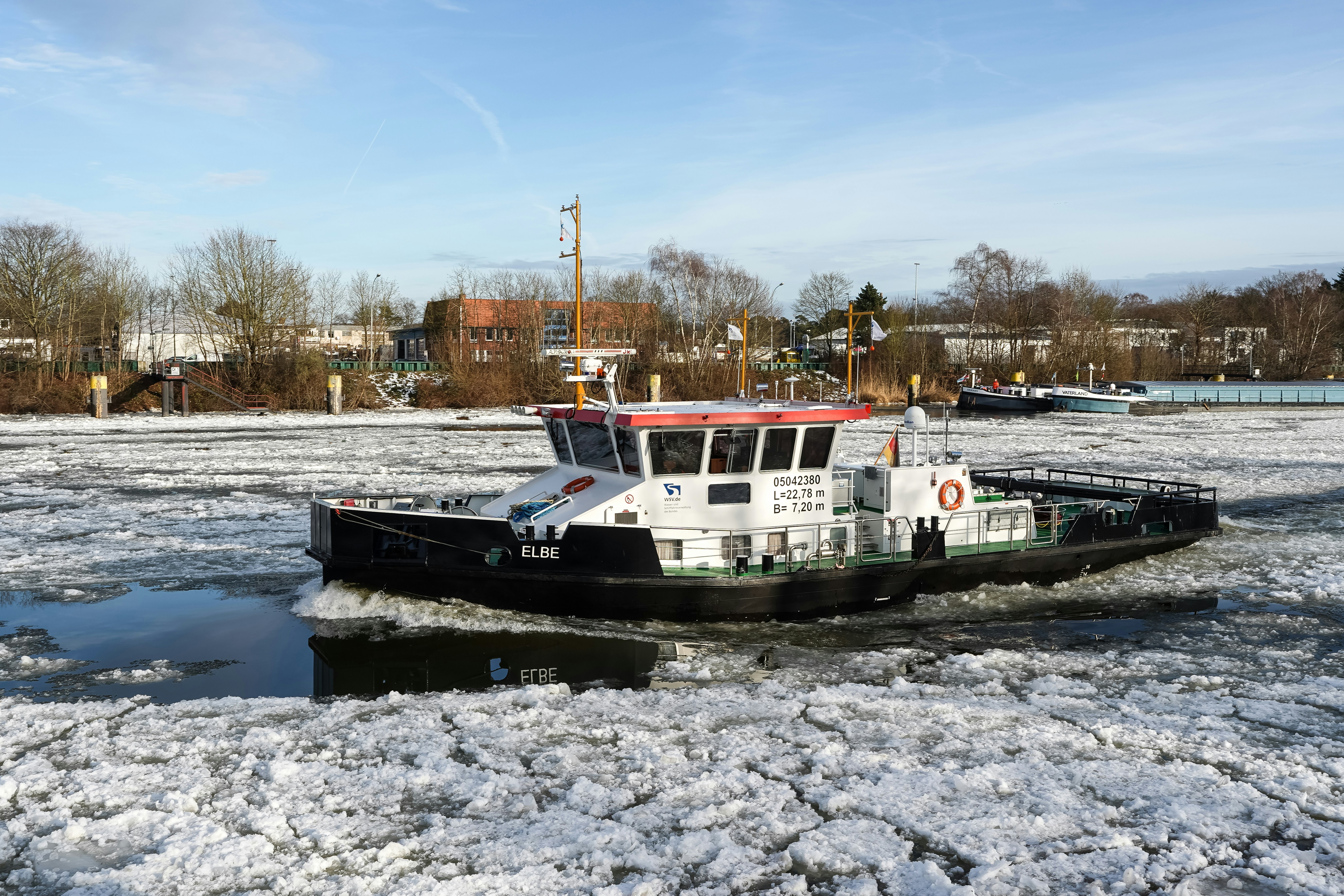 Tugboat navigating through icy water on a sunny day