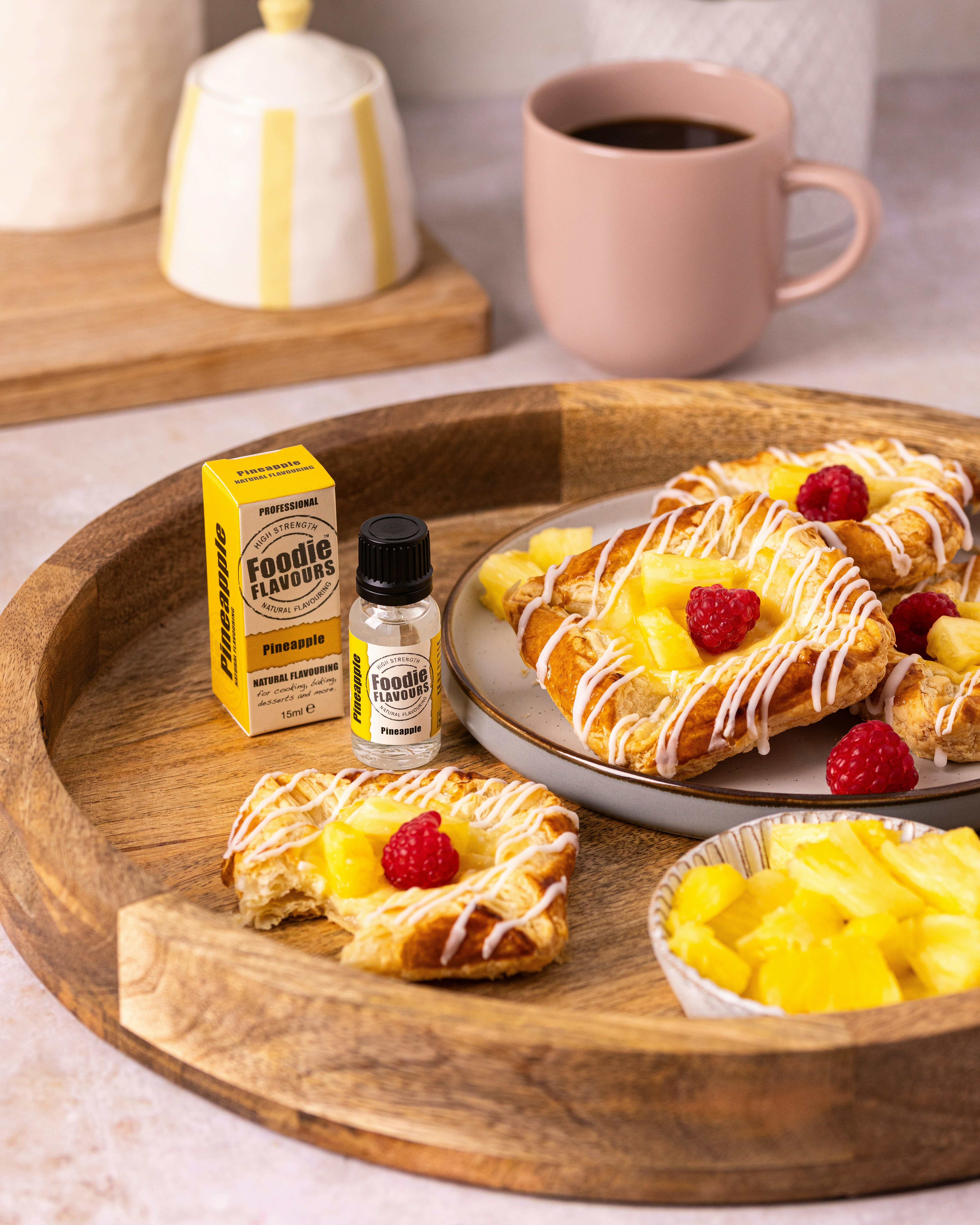 Pastries with pineapple, raspberries, and flavoring on a wooden tray